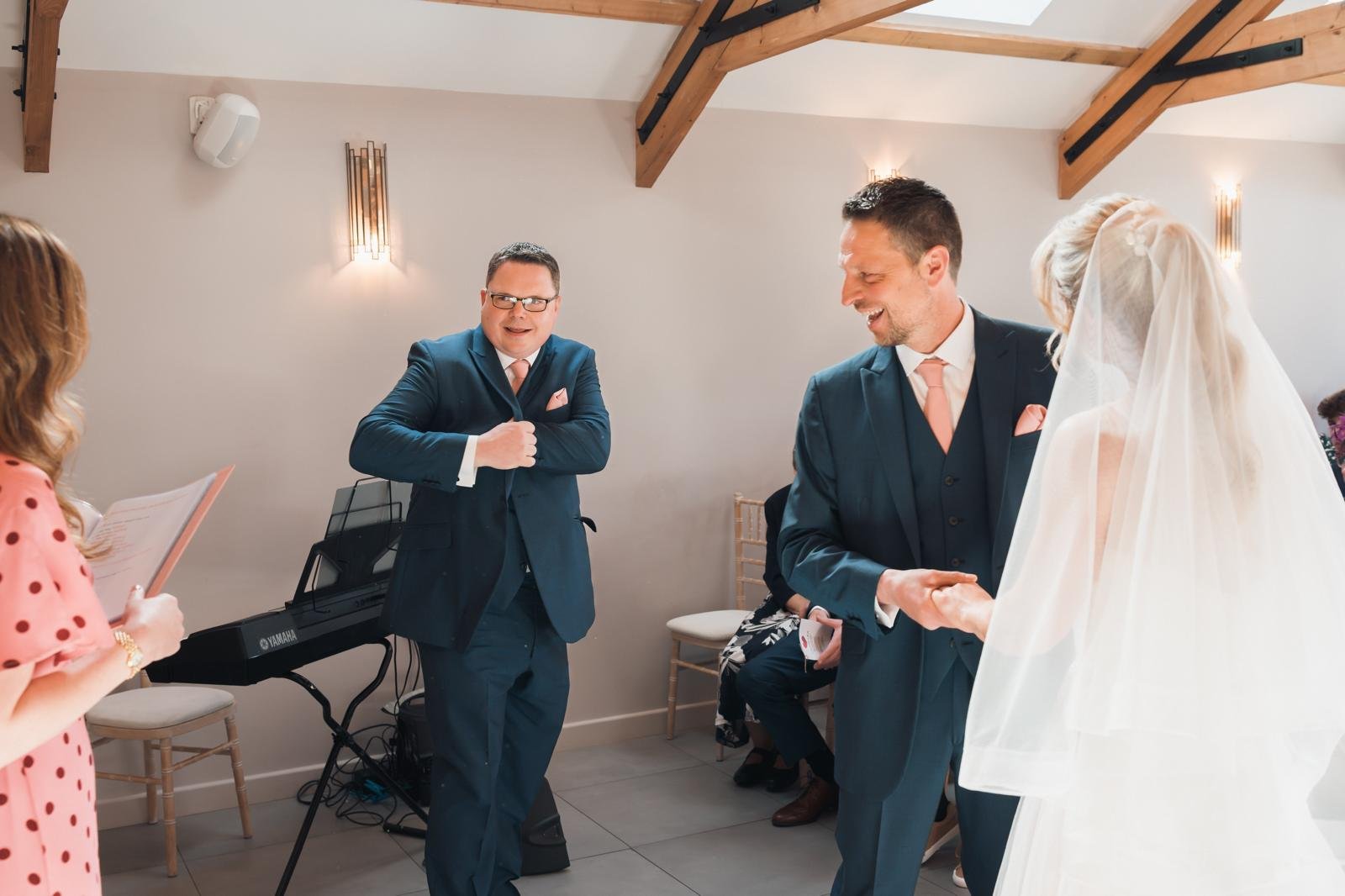 Best man looks for rings during wedding ceremony surprise ring bearer moment. Guests and Surrey based wedding celebrant hunt for rings. 
Photo: Brown & Dixon Photography