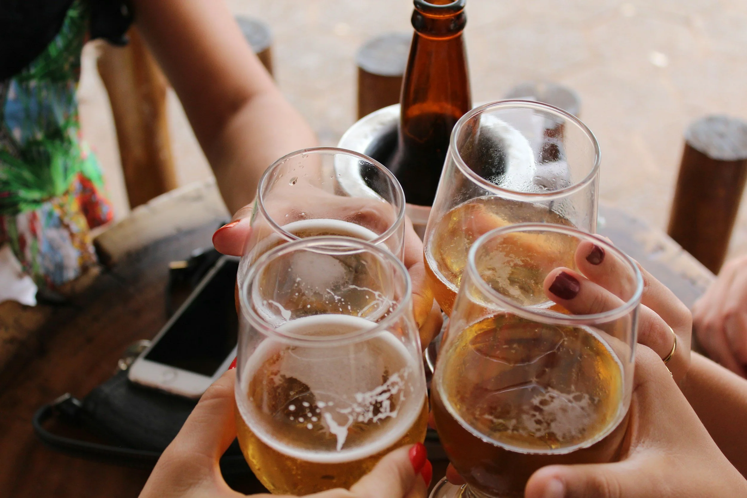 People raising glasses of beer in a toast at a social gathering.