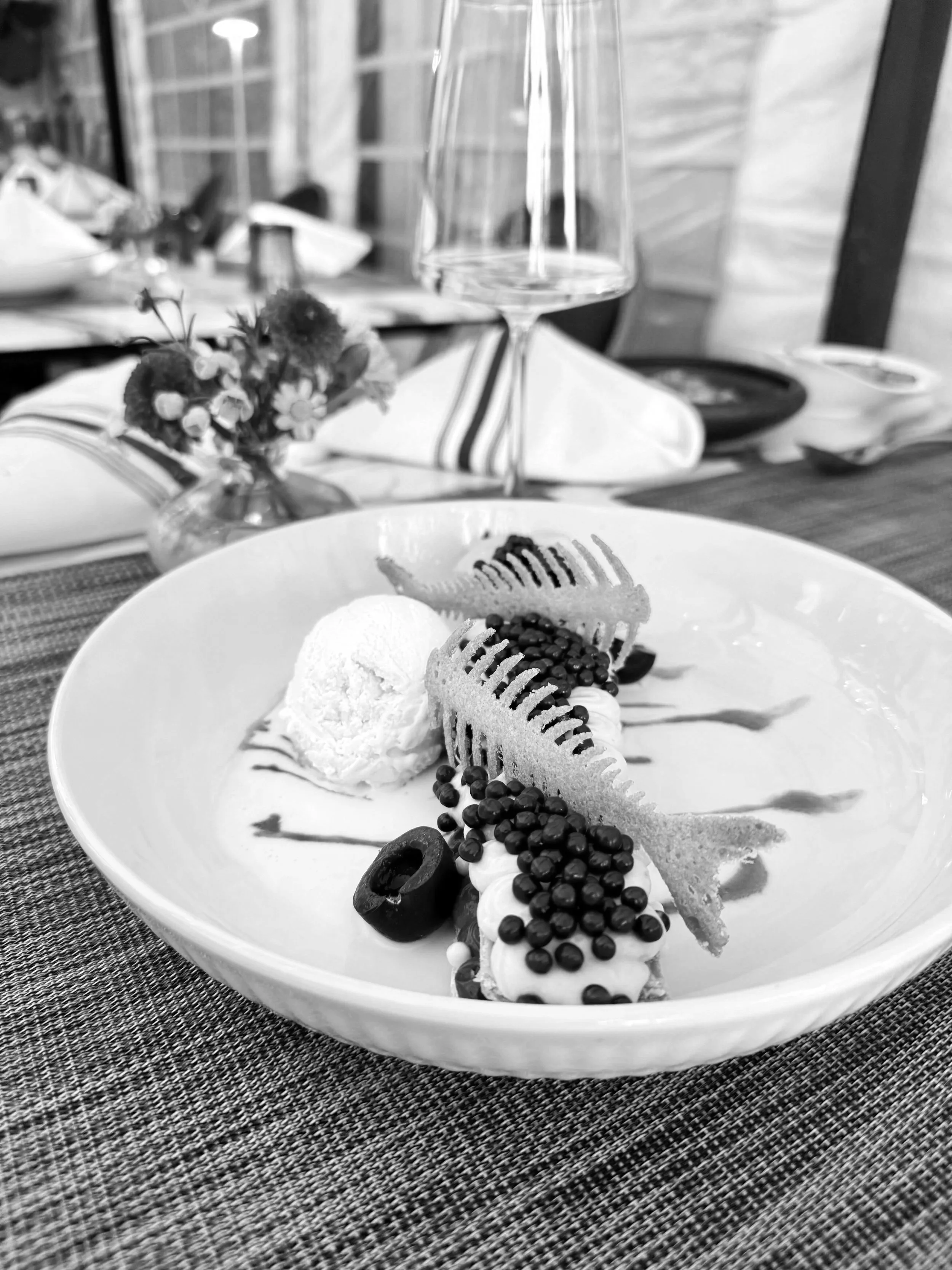 Dessert plate with ice cream, cookies, chocolate sprinkles, and sliced fruit in a restaurant setting.