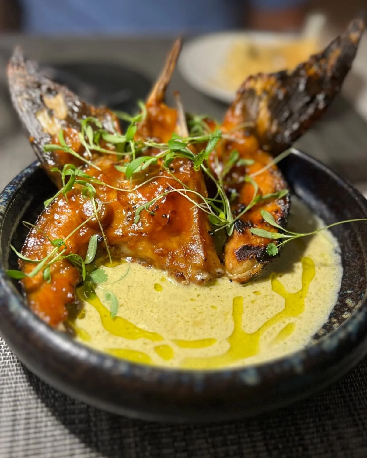 A prepared dish of crispy cobia collars in a curry coconut broth.