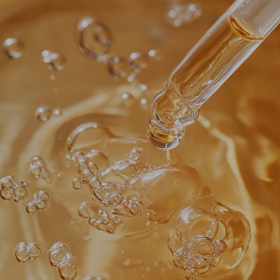 Close-up of a golden serum dropper releasing liquid with bubbles — representing The Lab Co Toronto’s Hydrafacial treatment, which infuses skin with nourishing serums for deep hydration, radiance, and rejuvenation.
