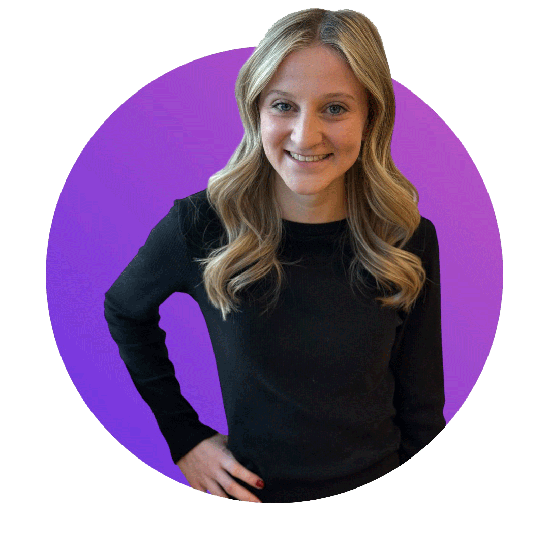 A woman with blonde hair wearing a black long-sleeve shirt, standing with her hand on her hip, smiling, against a purple circular background.