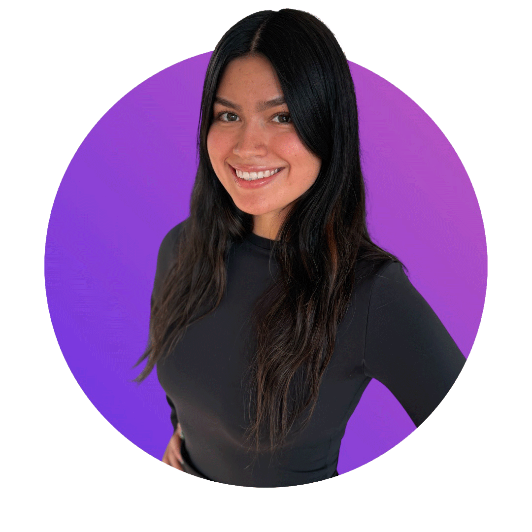 A smiling woman with long dark hair wearing a black top, standing against a purple background.