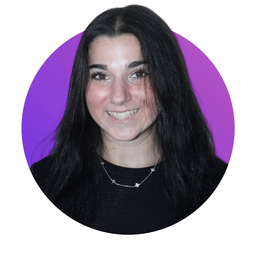 Portrait of a smiling young woman with long black hair, wearing a black top and a silver necklace, against a purple background.