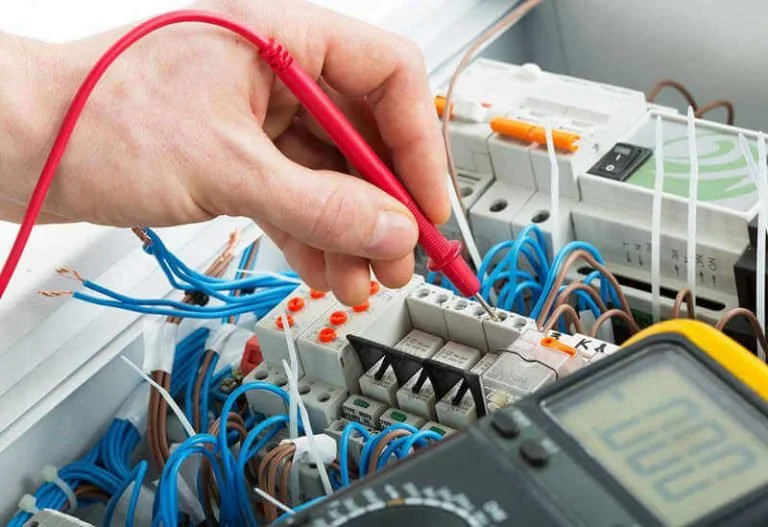 Person testing electrical circuit with a multimeter in an electrical panel.