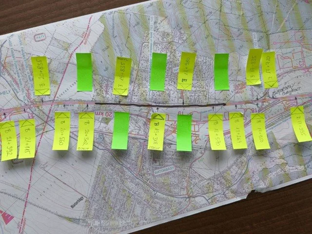 A map with yellow sticky notes containing handwritten measurements or data, and some green sticky notes arranged in a line across the map.