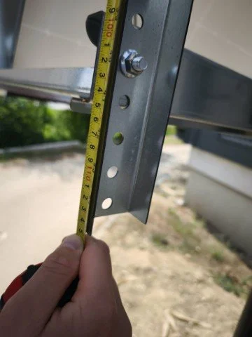 Person measuring a metal structure with a tape measure outdoors