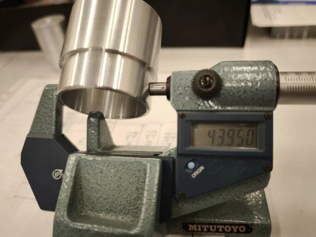 A digital dial indicator measuring 43.950 on a Mitutoyo precision measuring instrument.