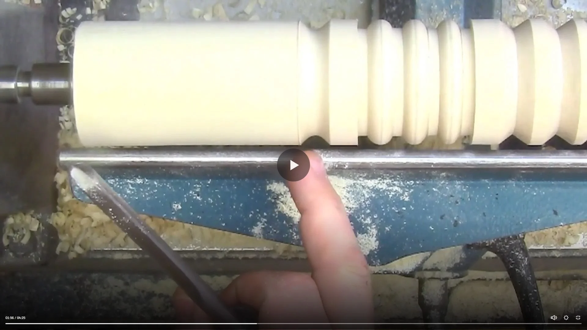 A person operating a pasta-cutting machine, guiding rolled-out dough with their finger as the machine cuts it into even strips.