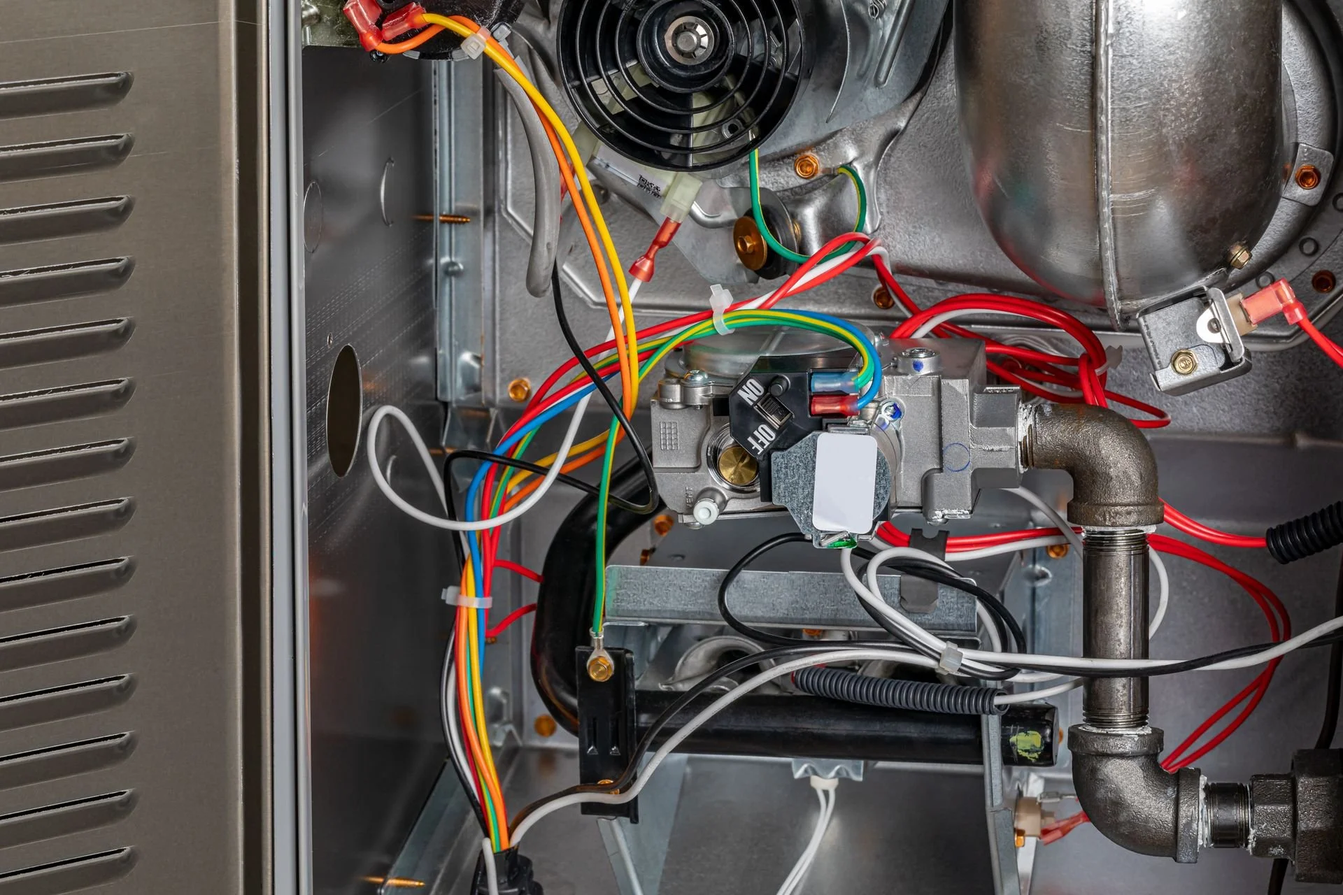Interior of an appliance showing wires, pipes, and mechanical components.
