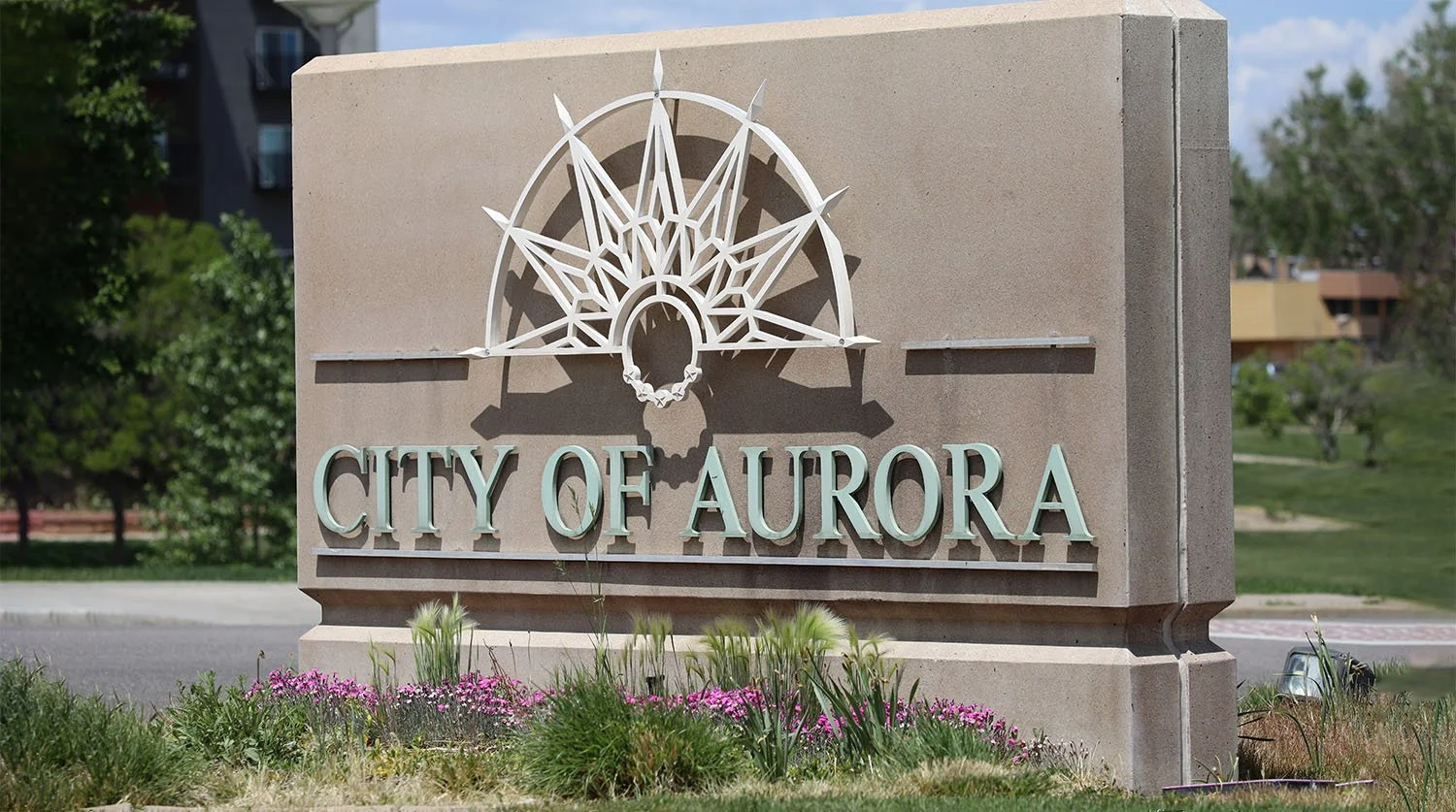 Block monument with a metal sign displaying City of Aurora