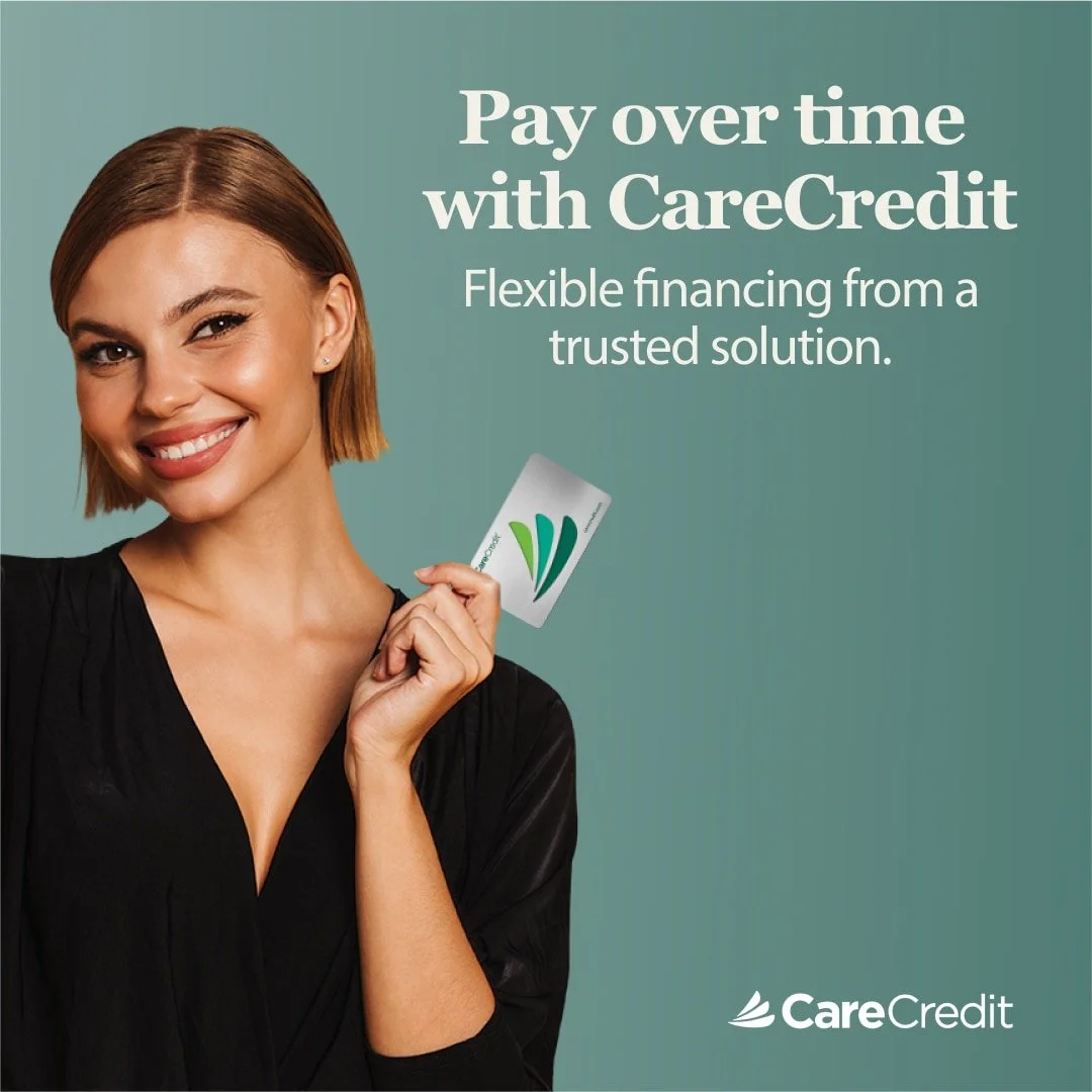 A woman with short brown hair smiling and holding a CareCredit card, promoting flexible financing options with CareCredit.
