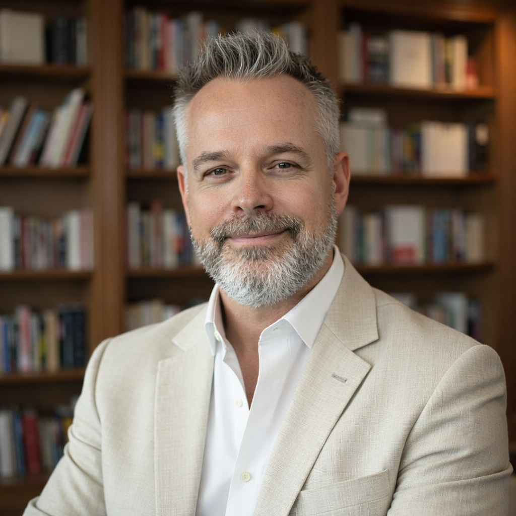 Professor RJ Starr, psychology scholar and author, seated in front of a library bookshelf