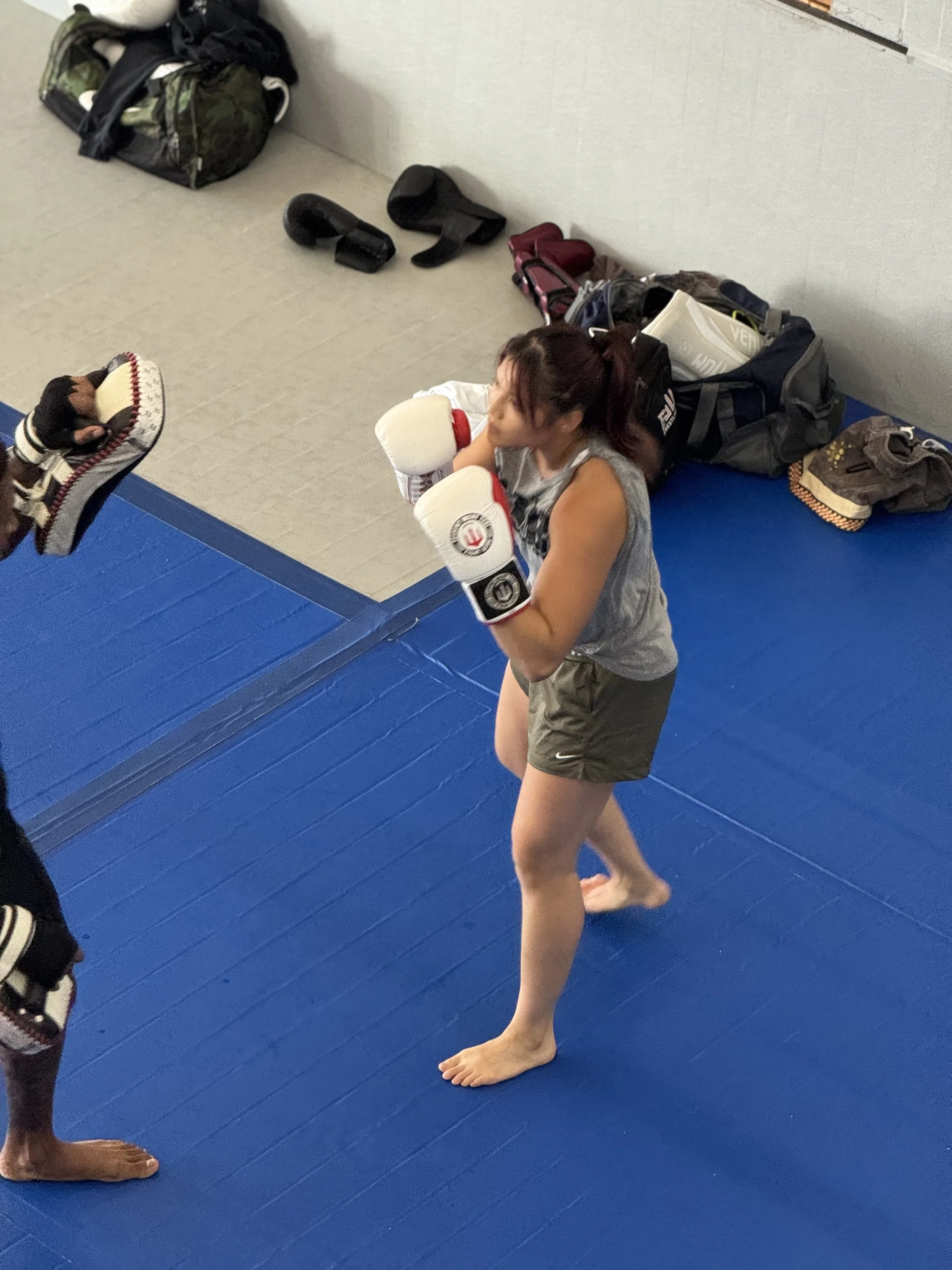 Black and white photo of a person with braided hair, focusing intensely as they throw a punch towards the camera.