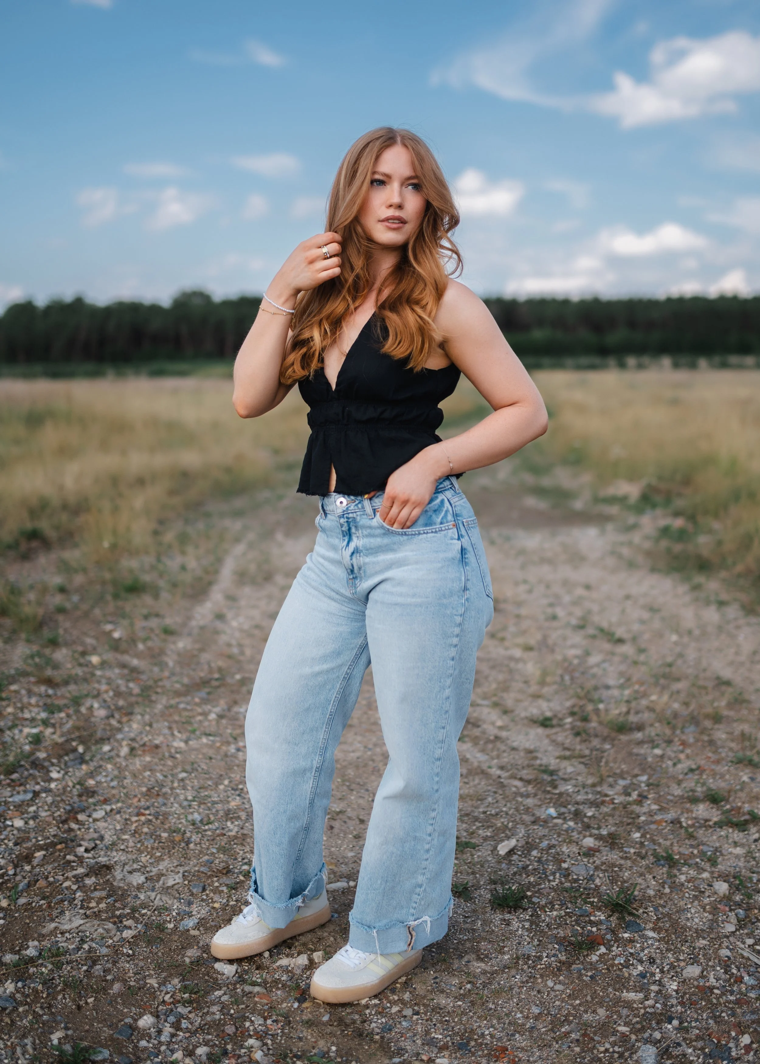  Outdoor Portrait Oberpfalz, Maggi in heller Wide-Leg-Jeans auf einem Feldweg am Steinberger See, blauer Sommerhimmel 