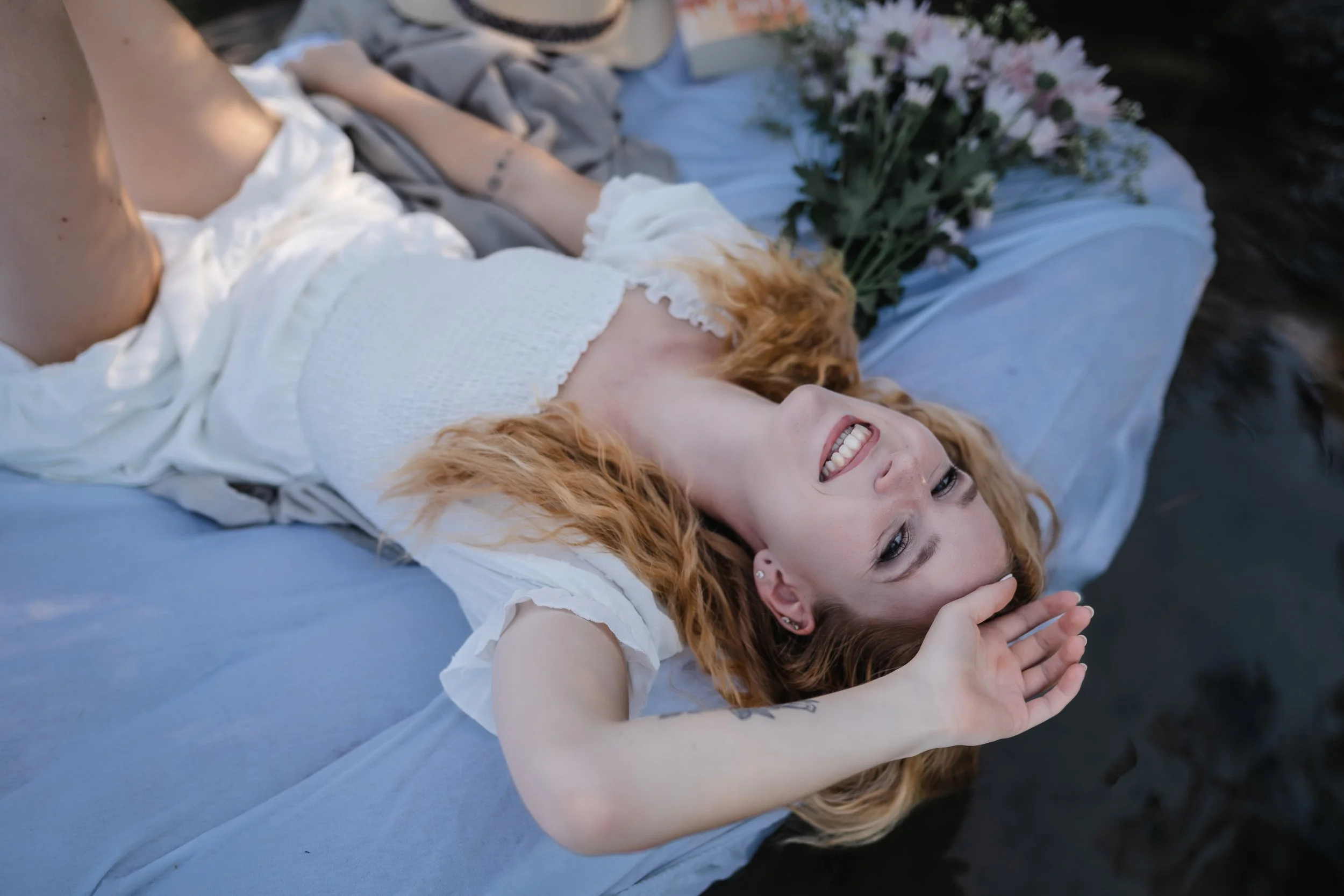 portrait-shooting-steinberger-see-luftmatratze-weisses-kleid-07.jpgTina im weißen Kleid auf einer Luftmatratze im Steinberger See mit Blumen und Buch.