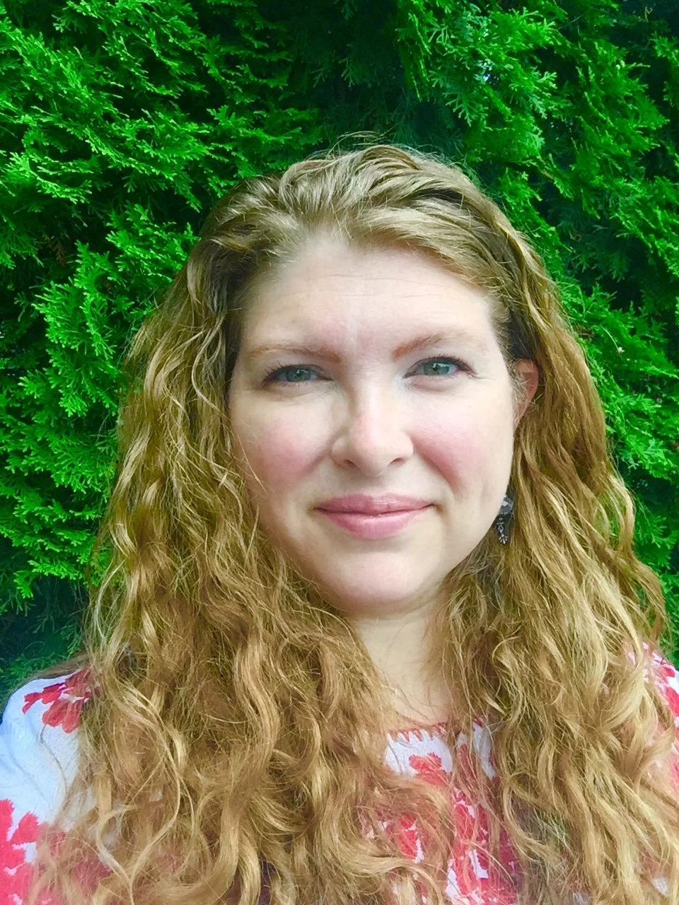 Colorful singing bowls placed on a patterned cloth on a table, with a small mallet beside the green bowl, in a room with green walls and a window.
