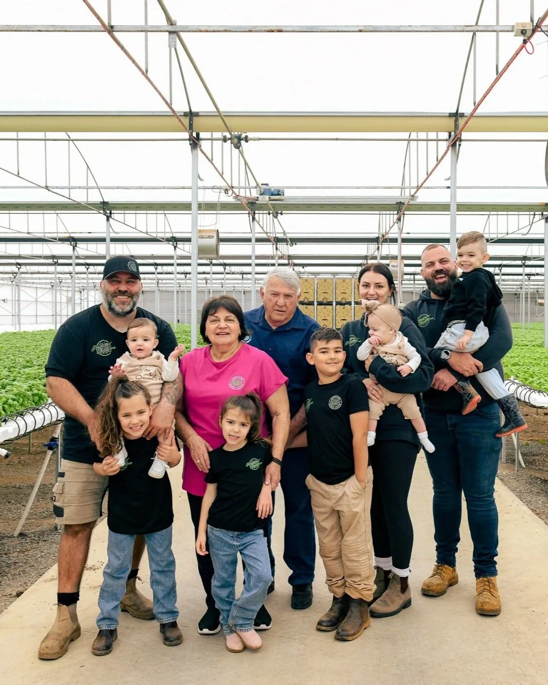 Adelaide Hydro Fresh family inside a greenhouse with green plants in the background.