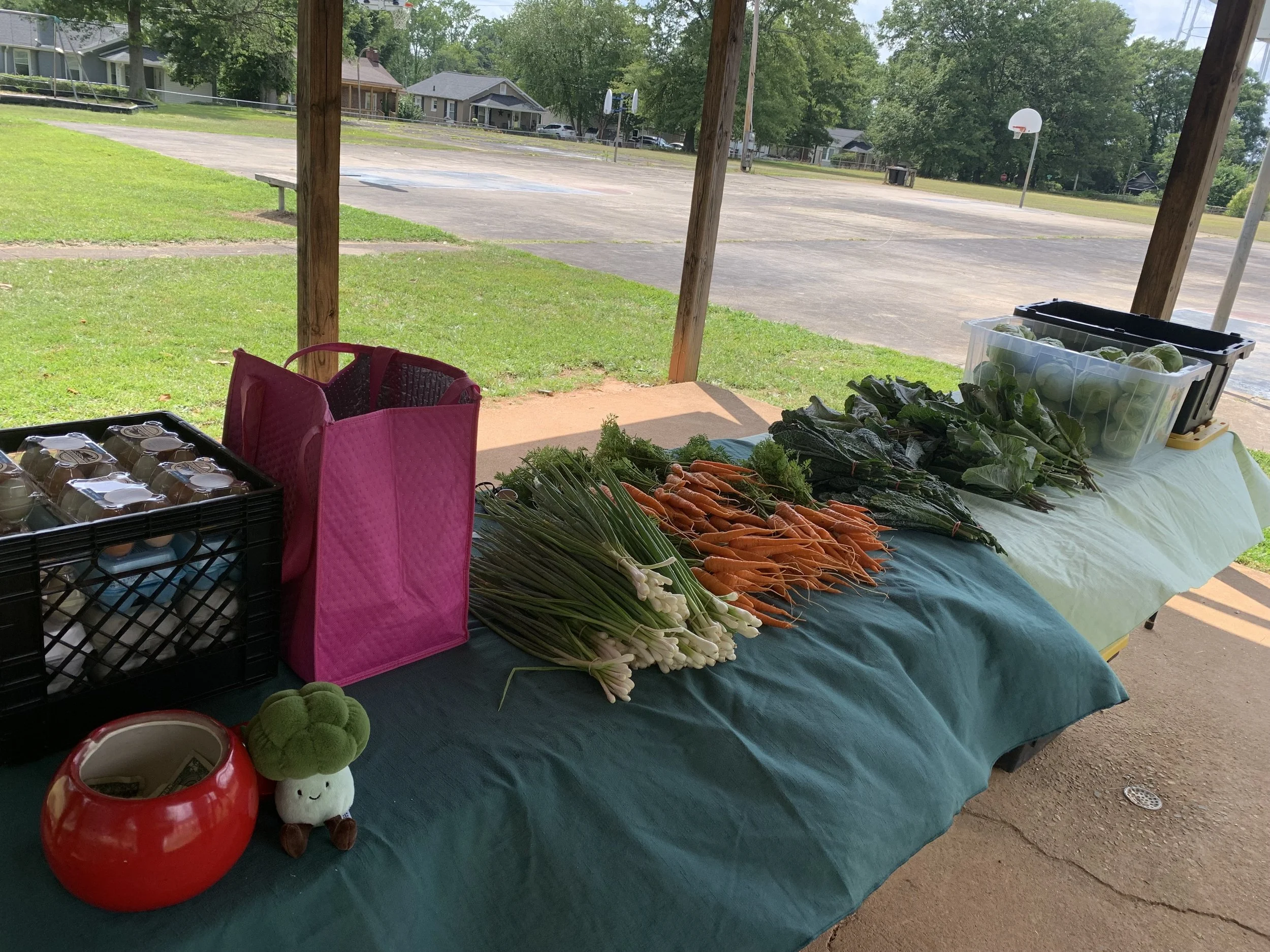 A crate of eggs and various produce laid out on tables with green table cloths