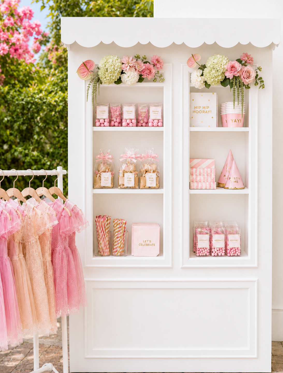 Decorated party display with pink and white theme, featuring flowers, party favors, and party hats with pastel-colored boxes and striped straws.
