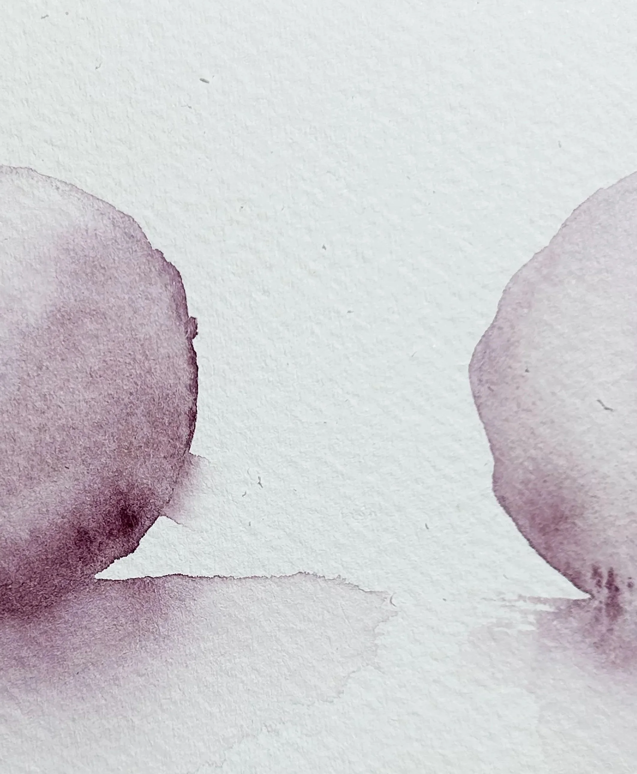 Close-up of watercolor paint with soft purple and pink hues blending on textured paper.