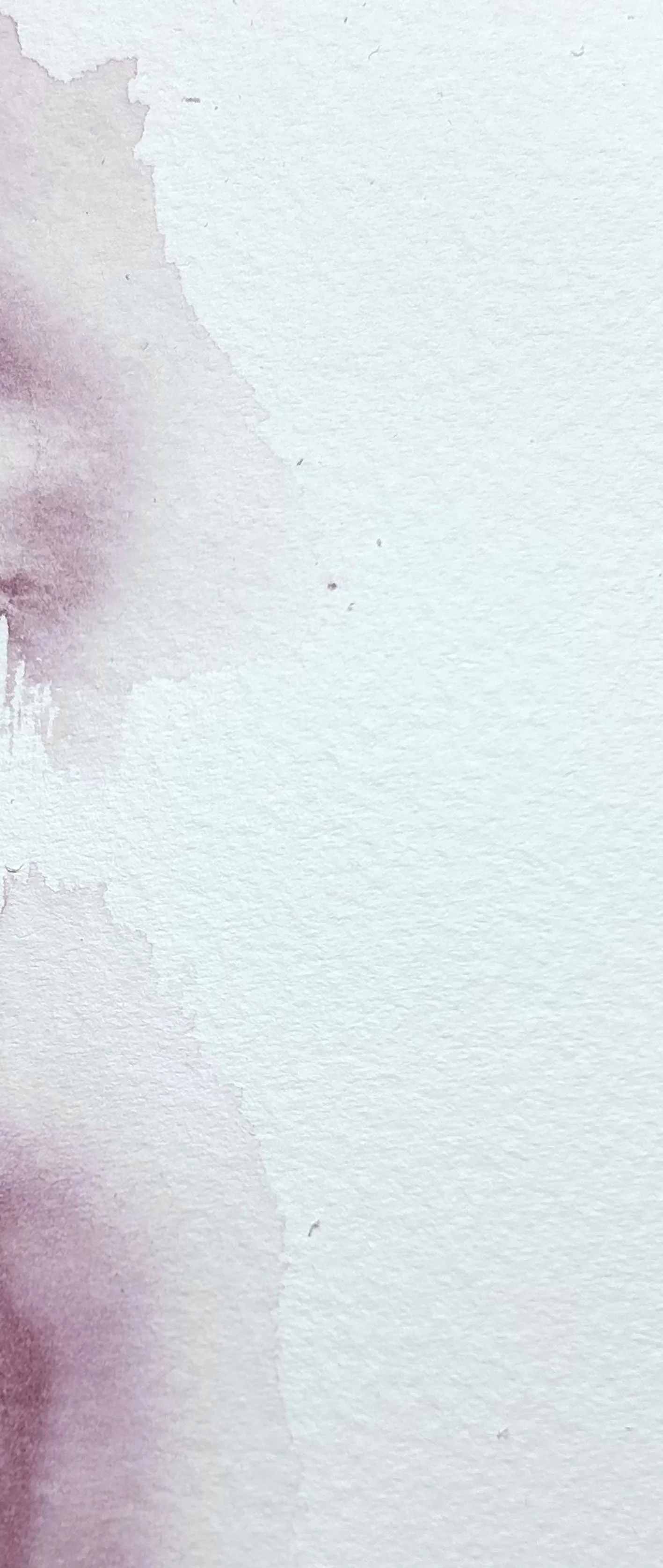 Close-up of a white textured paper with some purple watercolors on the left side.
