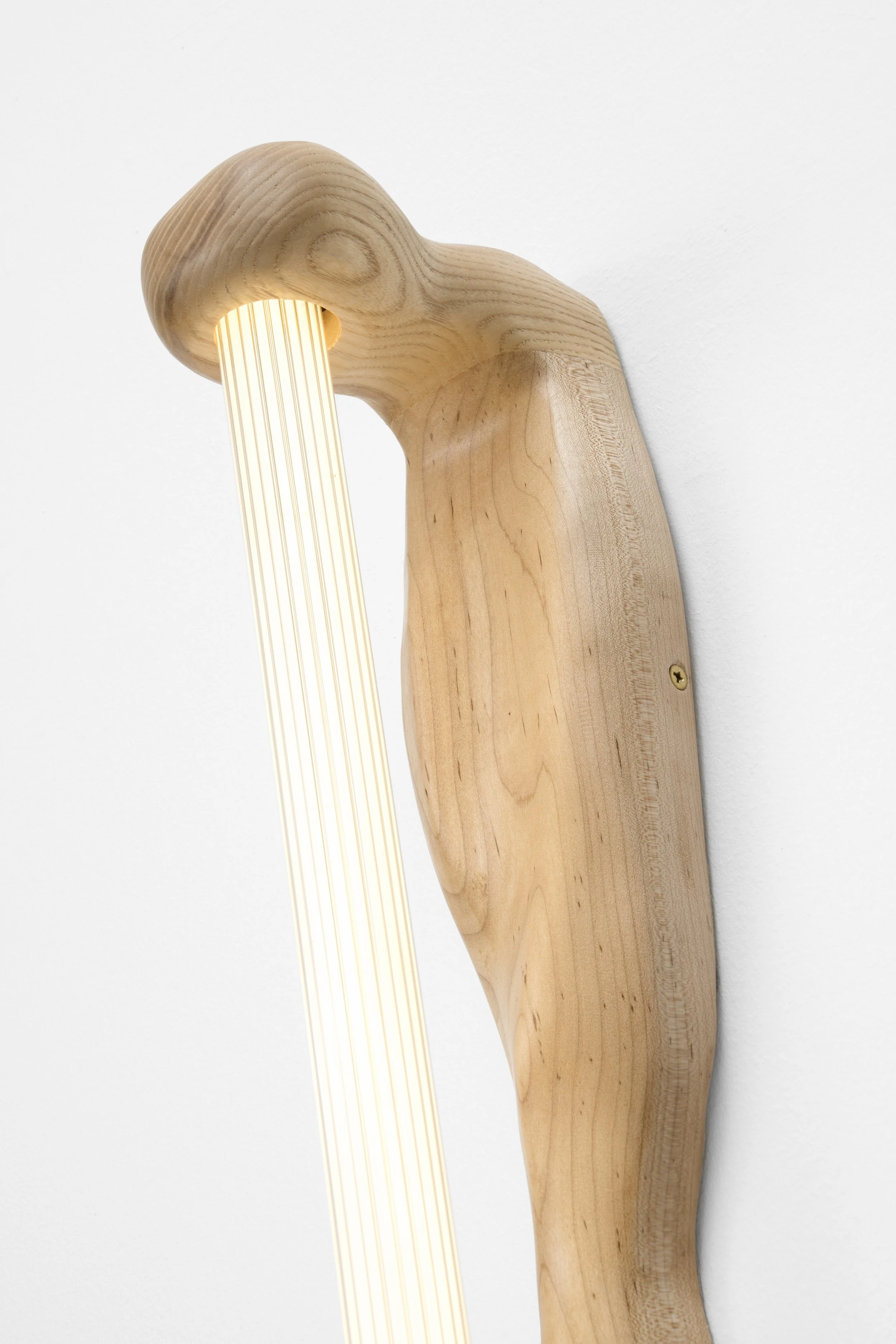 Wooden wall lamp shaped like a bird with a light stream coming from its beak.