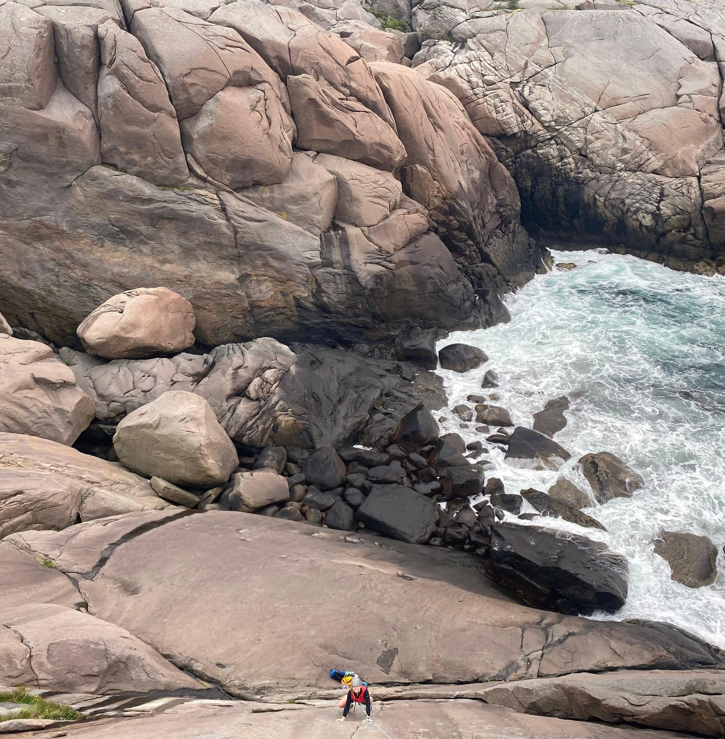 Amelia climbing with the waves crashing underneath her