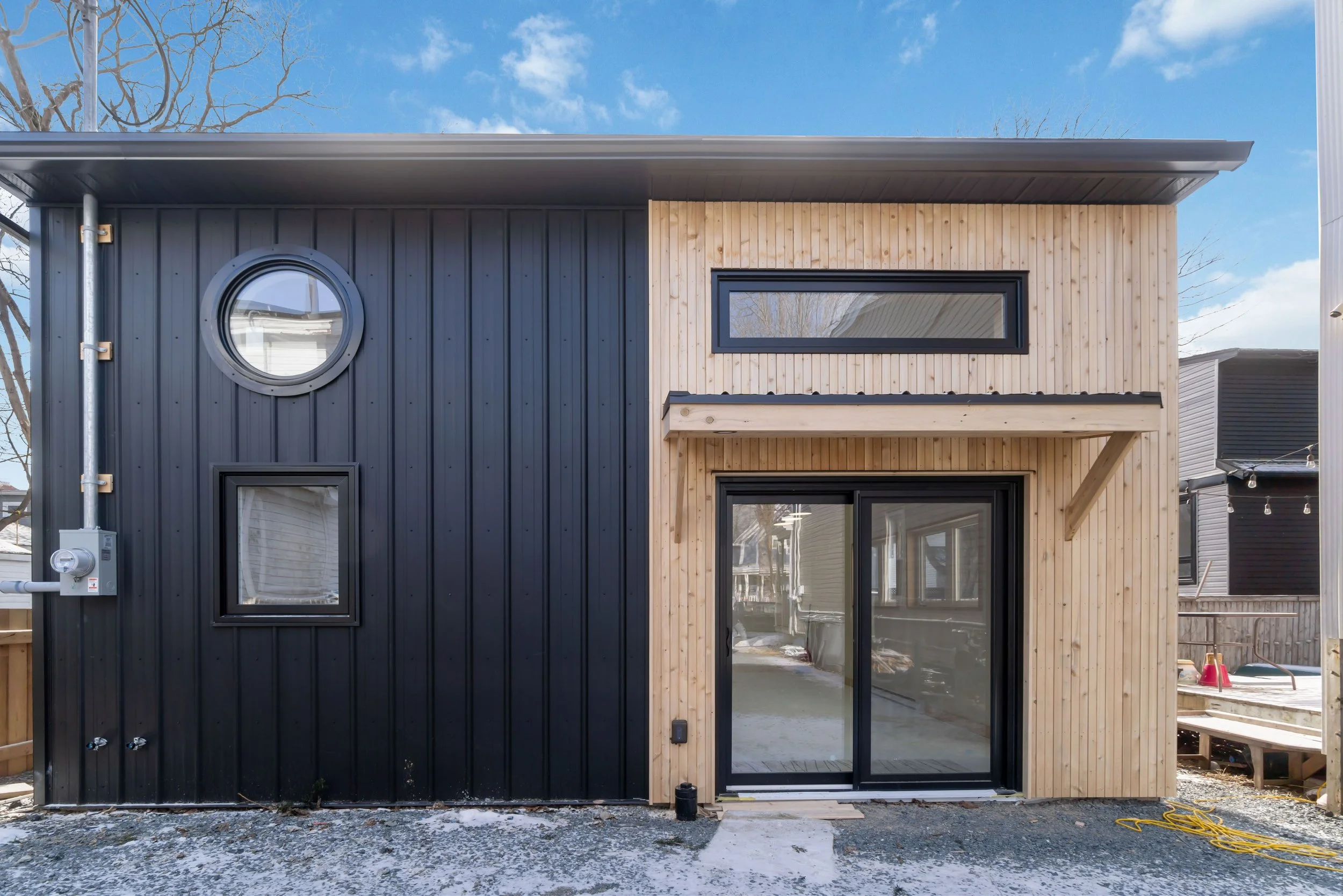 Backyard suite with a combination of wood and metal siding, and black window frames.
