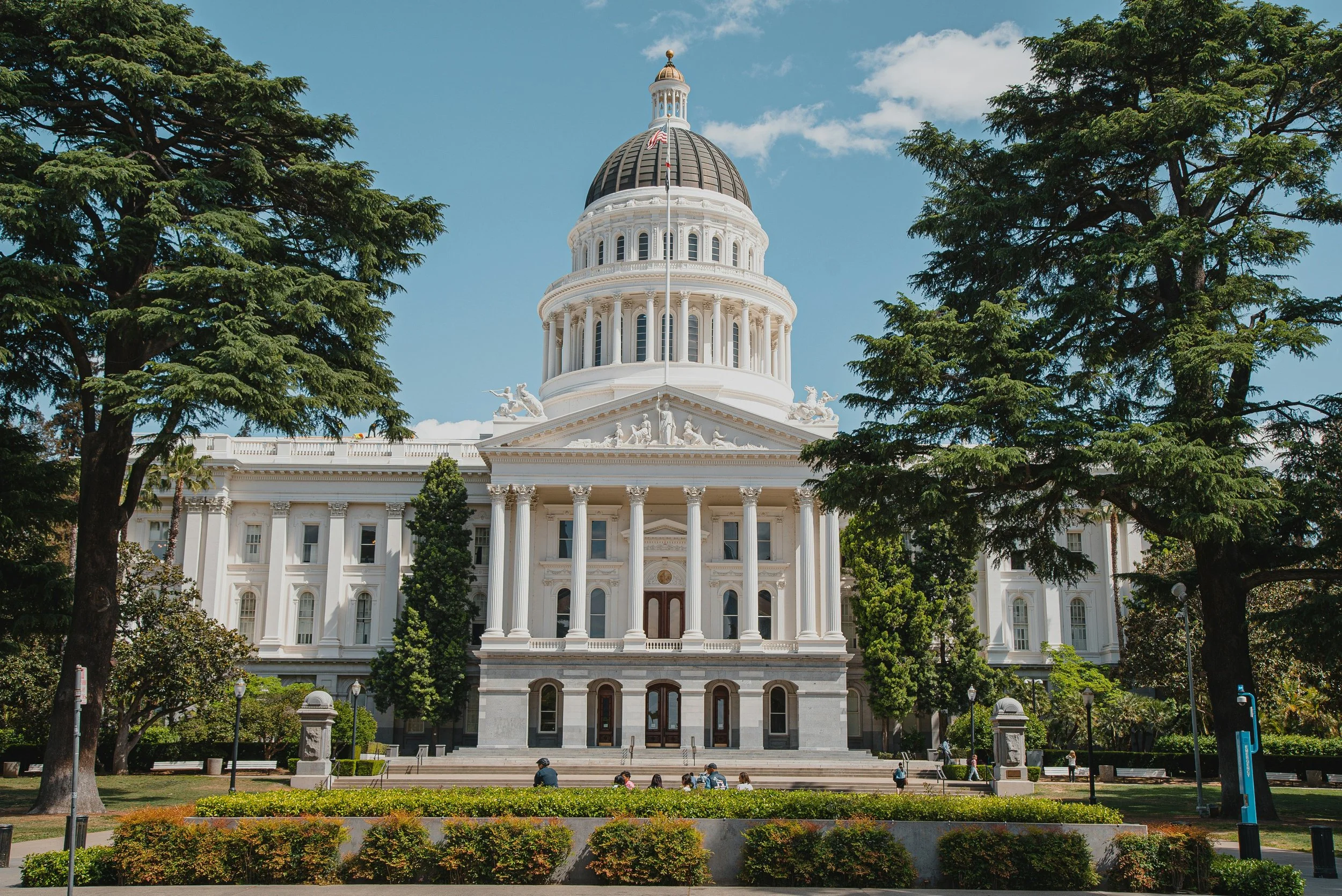 California Capitol with trees and greenery in foreground.
