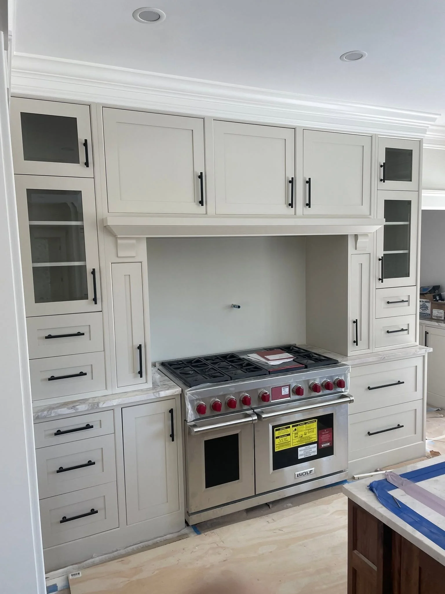 Kitchen with white cabinets, a stove, and a countertop, under construction or renovation.