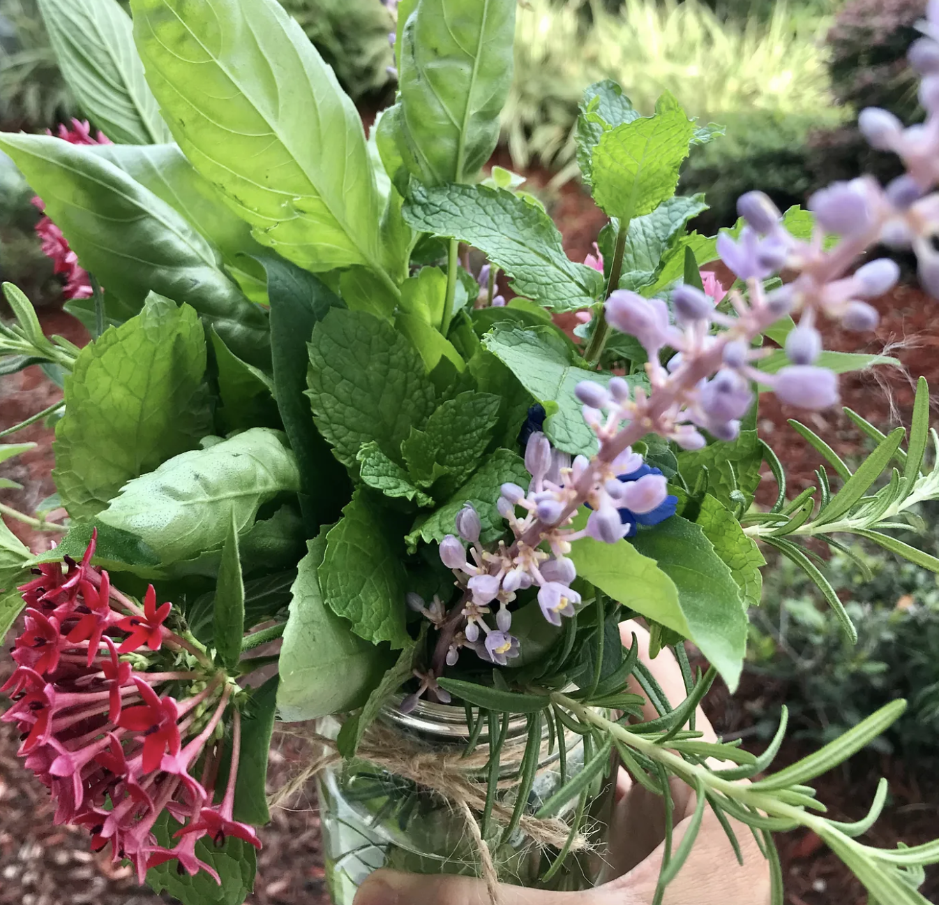 Beautiful flower arrangement with purple and pink flowers and green foliage in a mason jar