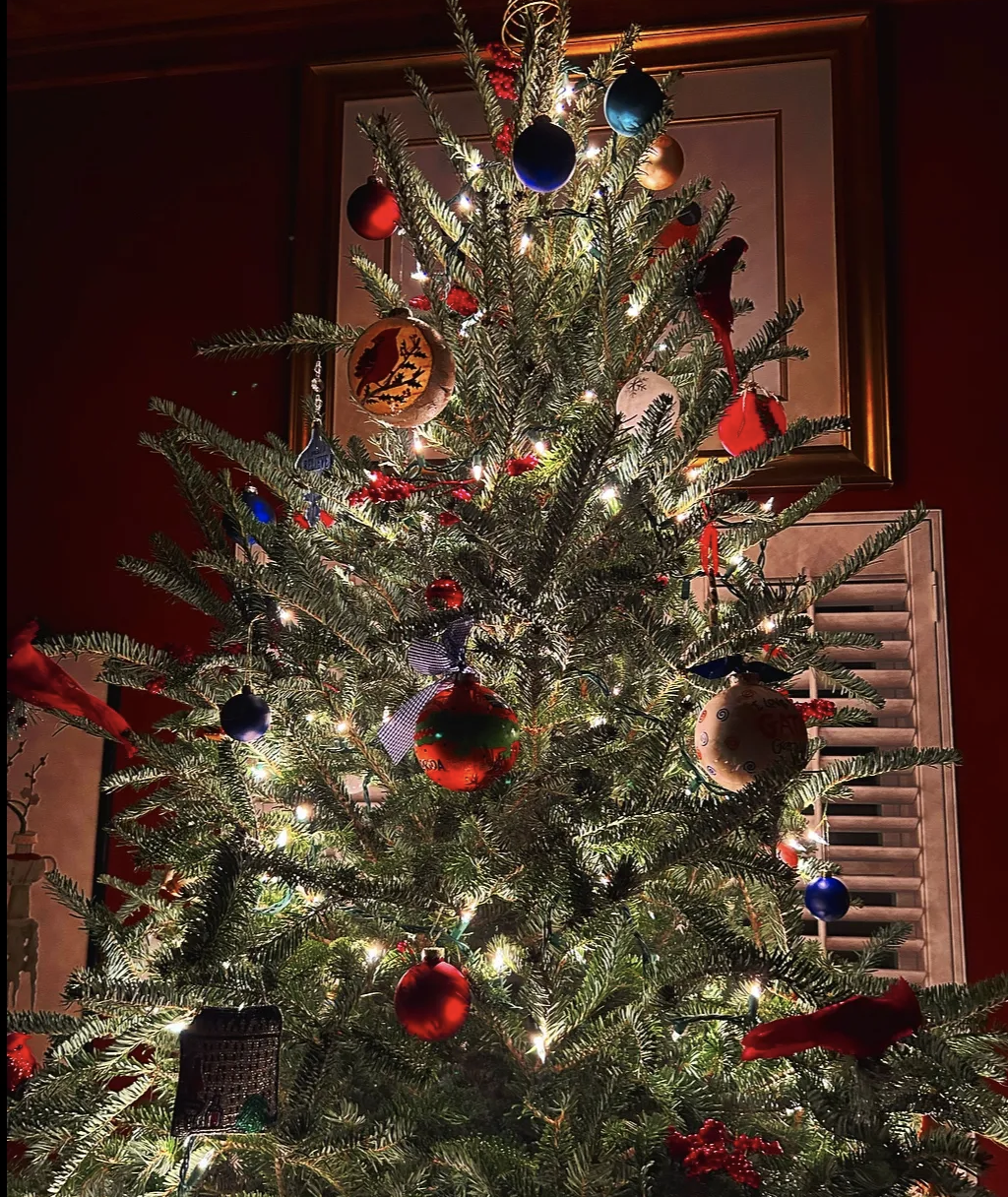 A decorated lit up Christmas tree with mismatch ornaments in a dark room
