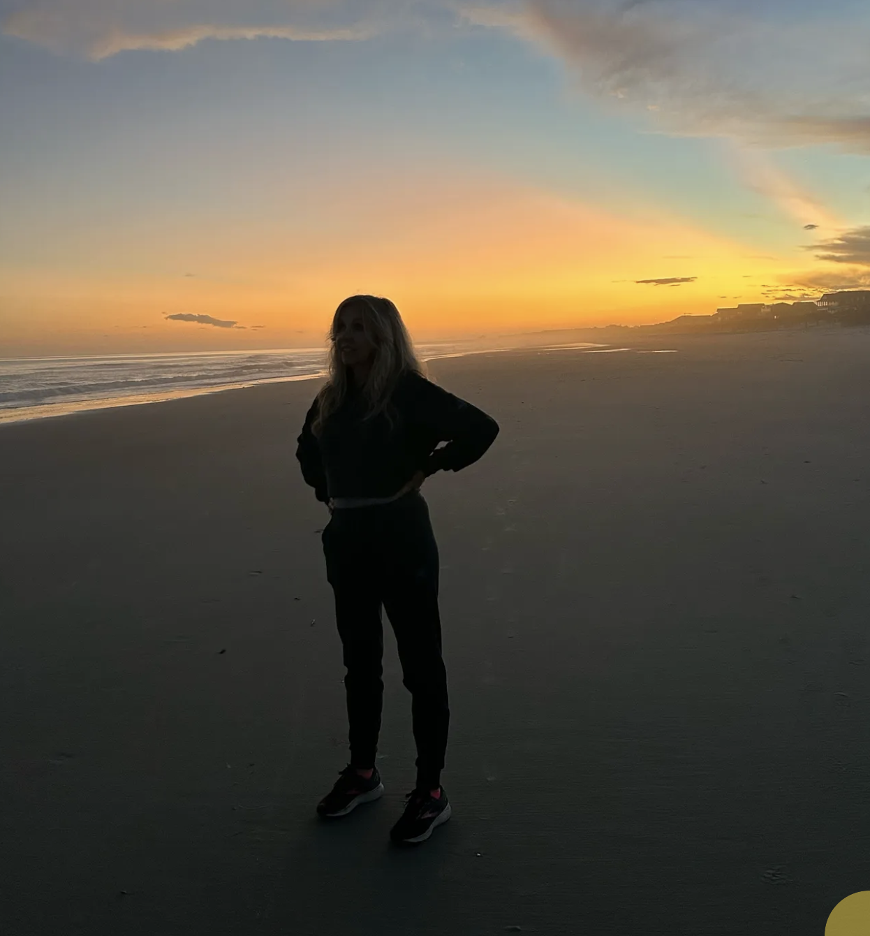 Kirsten Nelson Telan standing on the beach with a sunset behind her