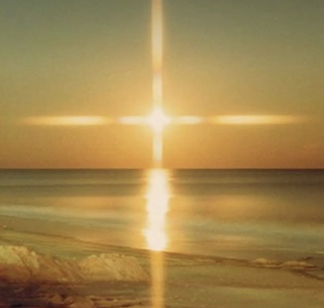 Photo of the sunshine making a glowing cross in the sky over water