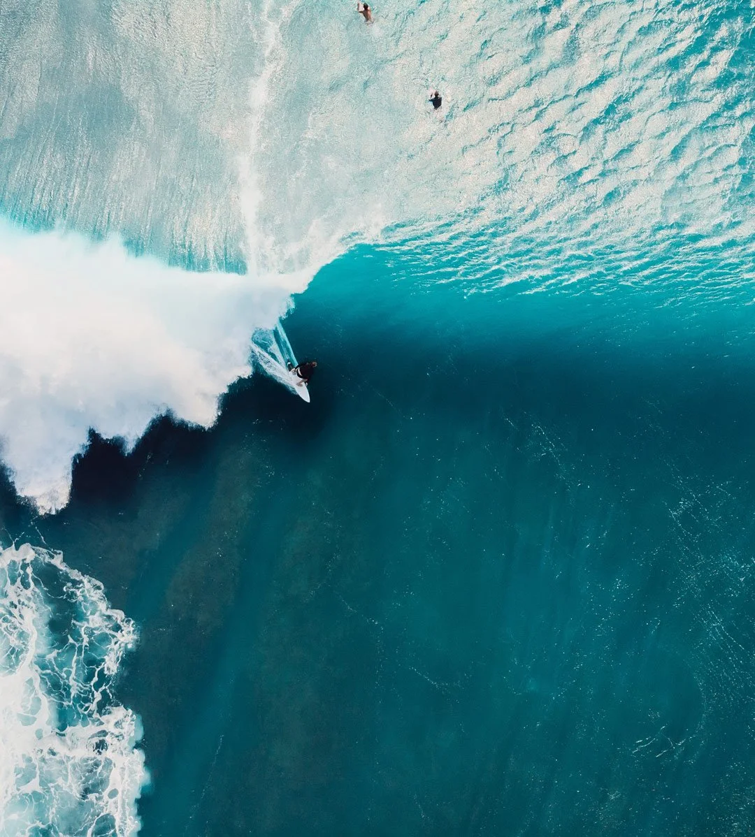 Ein Surfer reitet eine große Welle im Meer, Blick aus der Vogelperspektive.