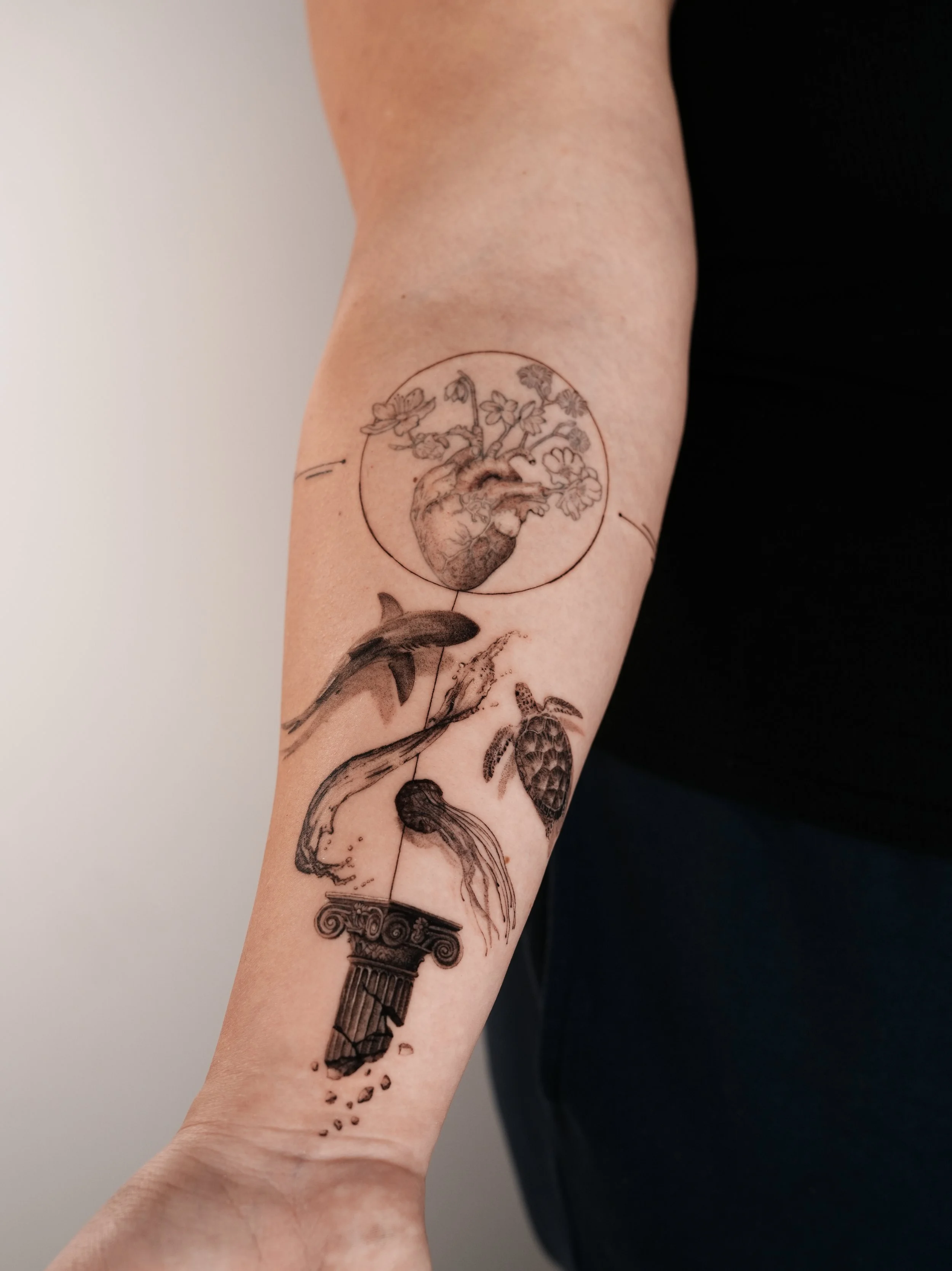 Tattoo of an anatomical heart with flowers in a circle, a jumping fish, a sea turtle, and a broken Greek pillar on a person's forearm. Done by famous tattoo artist located in Financial District of New York City - Gregory Mirzoyan @gmtattooing