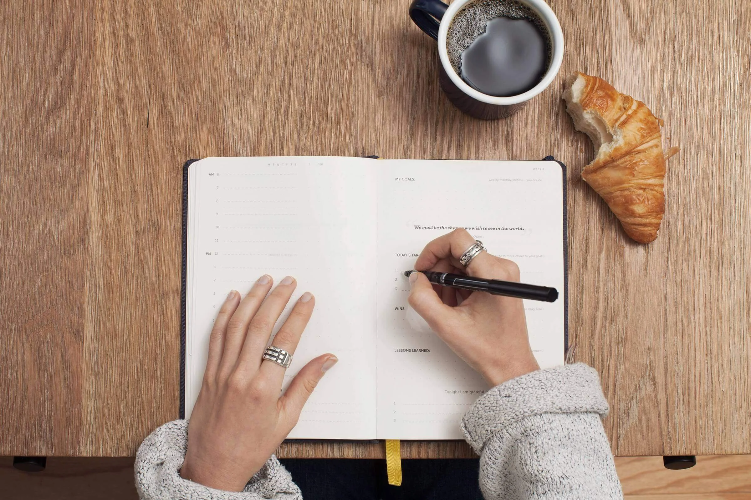 Author taking notes in notebook at desk with coffee
