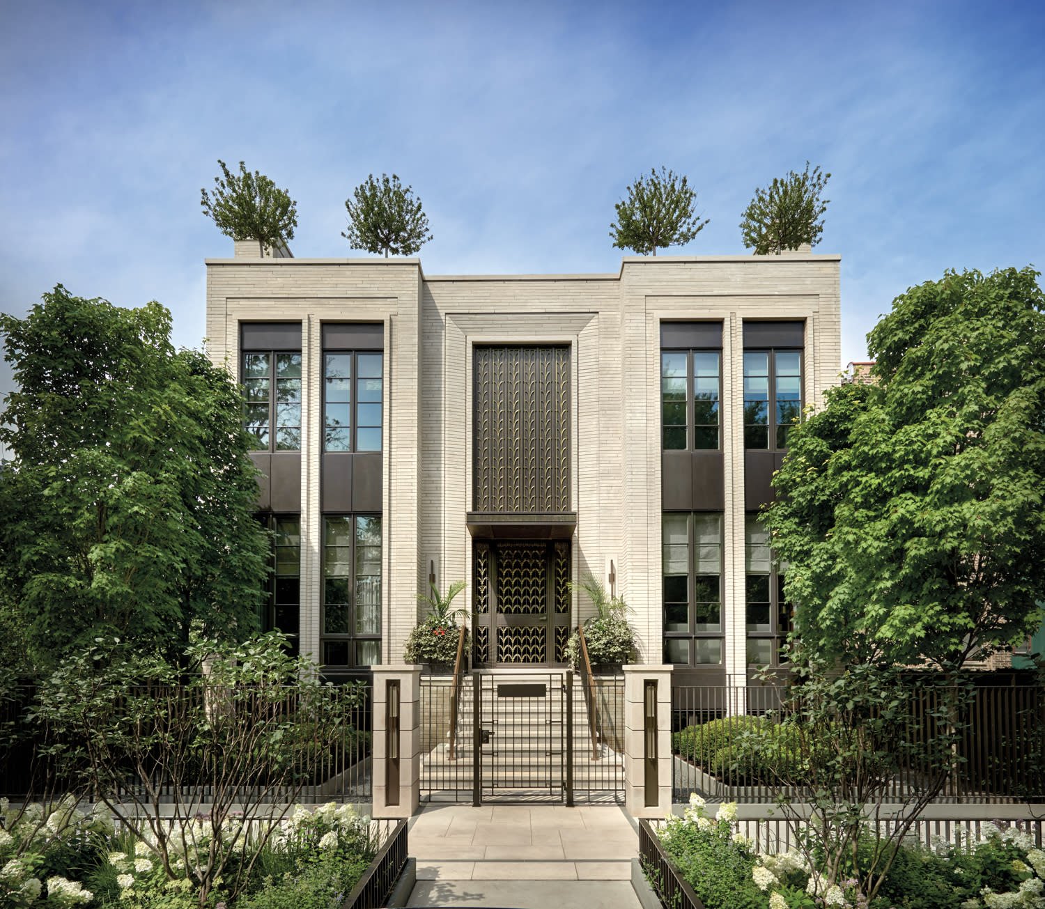 Elegant modern house with large windows, ornate front door, landscaped garden, and trees on the rooftop.