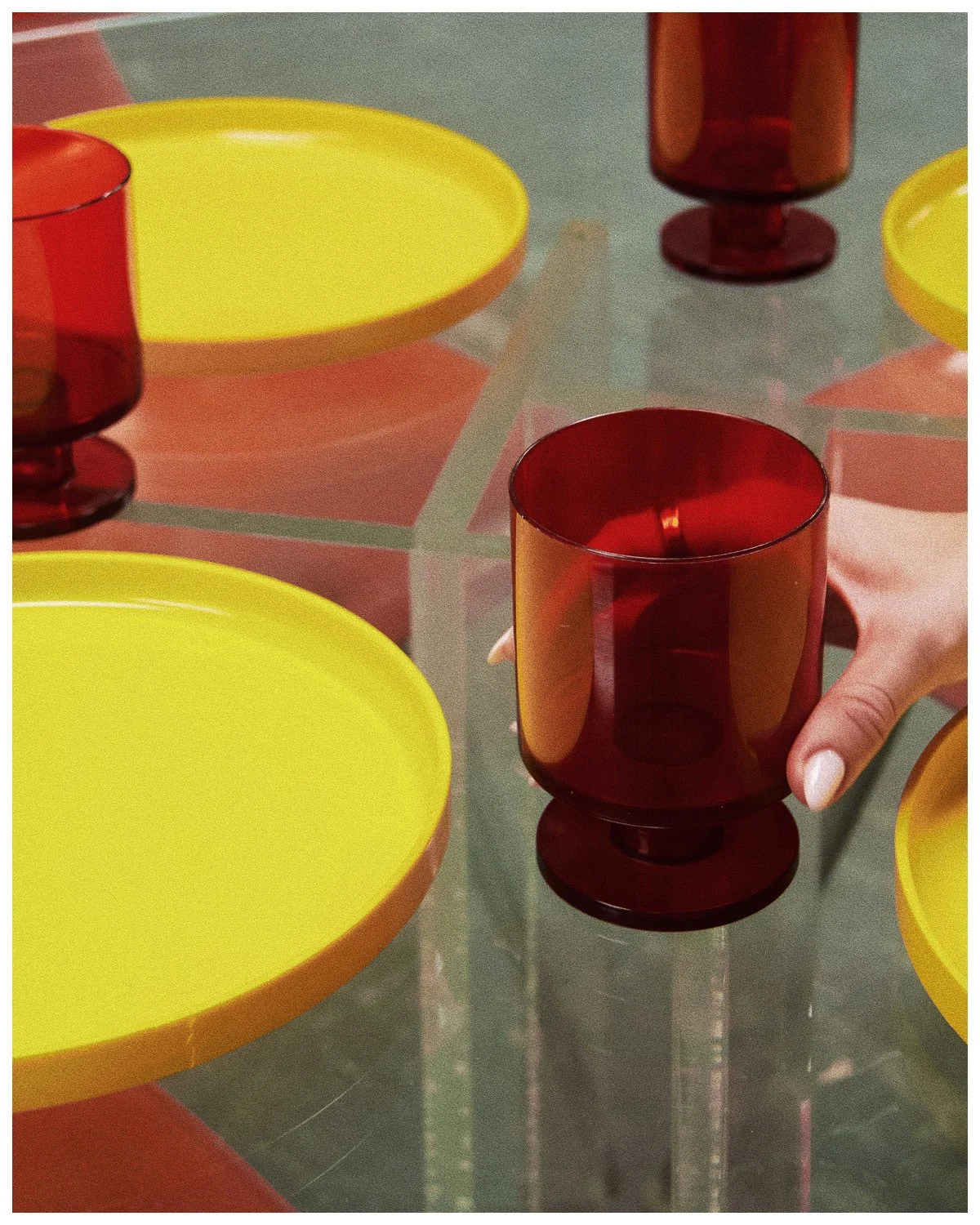 Red glasses and yellow plates on glass table