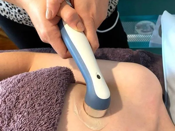 A person performs a cosmetic or medical treatment on a person's chest using a handheld device.