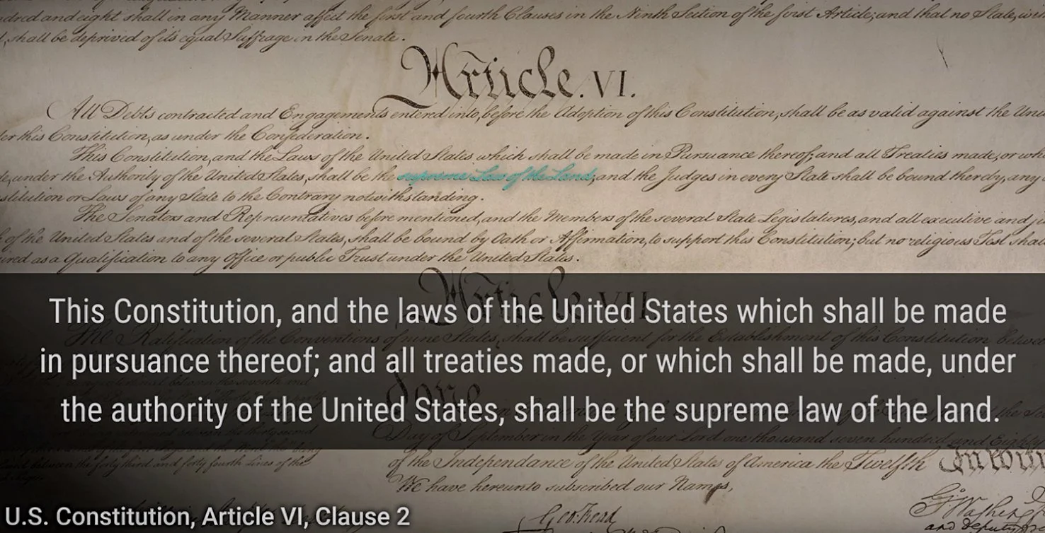 Close-up of a handwritten historical document with the section title "Article VI" in large, stylized script. An overlay text states that it is from the U.S. Constitution, Article VI, Clause 2, and mentions the supremacy of the Constitution and federa