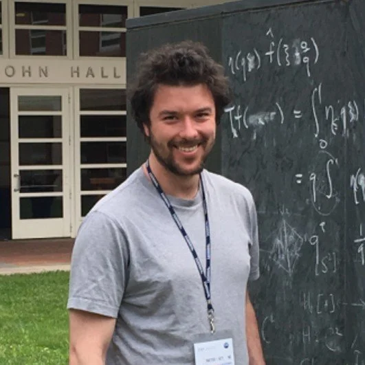 Maxim Gilula in front of a chalk board with mathematical symbols