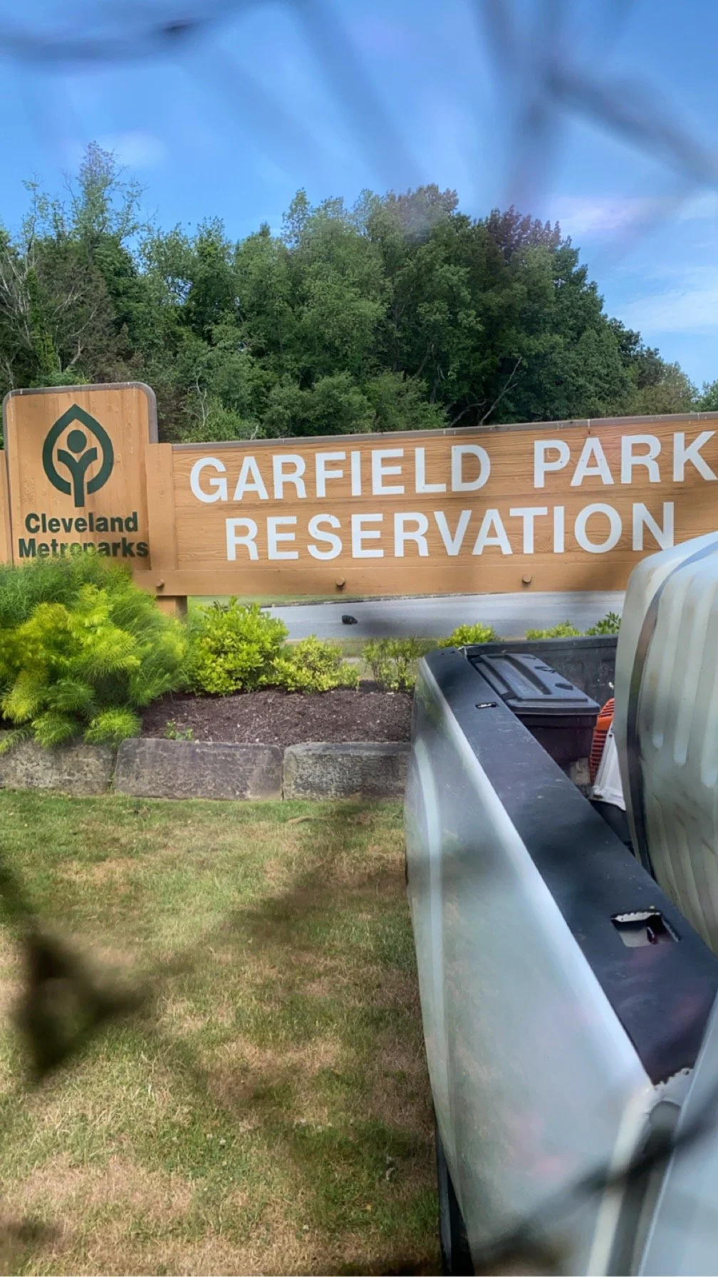 Sign for Garfield Park Reservation at Cleveland Metroparks, with a pickup truck in the foreground and trees in the background.
