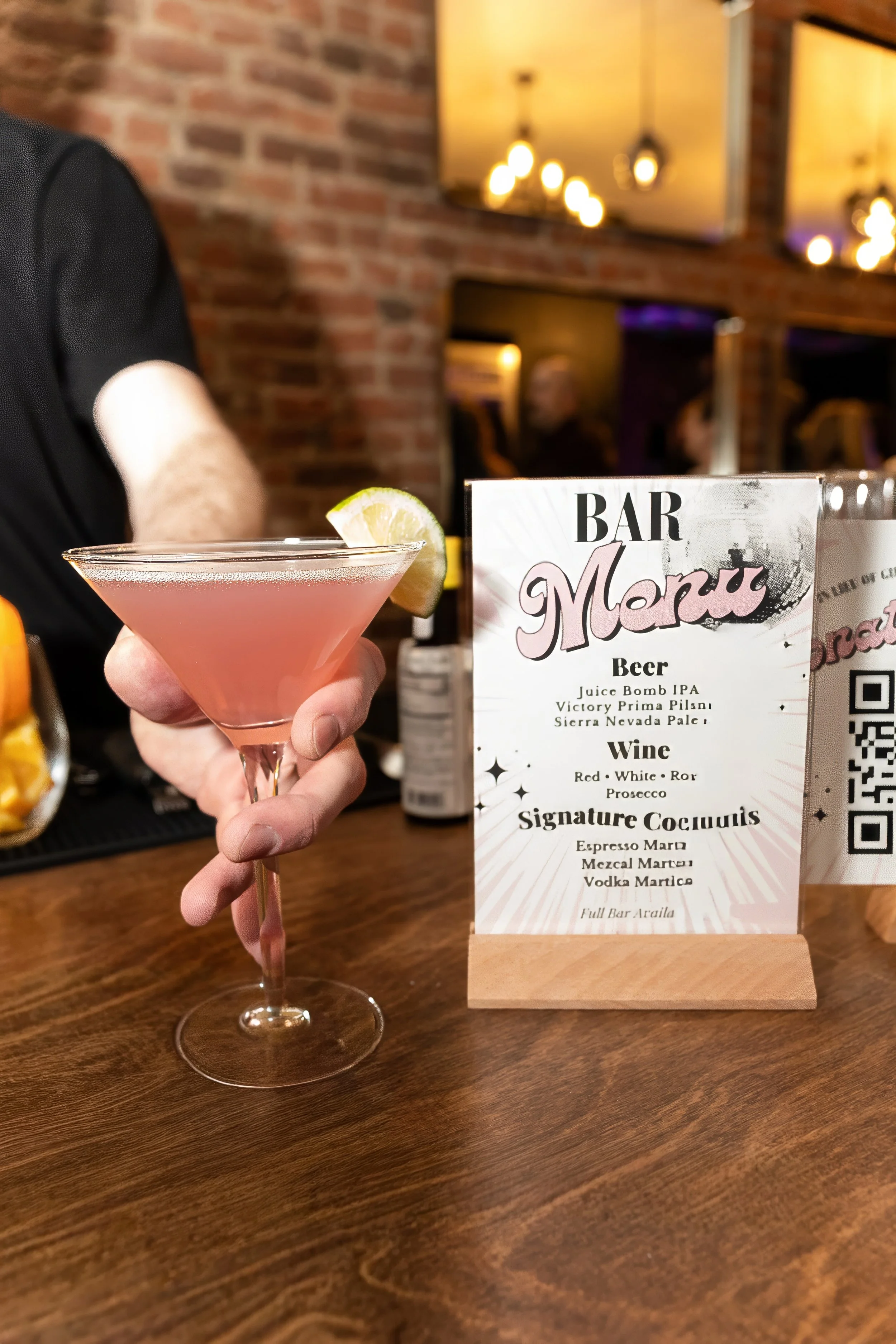 Close-up detail shot of bartender crafting cocktail next to custom drink menu at NYC even