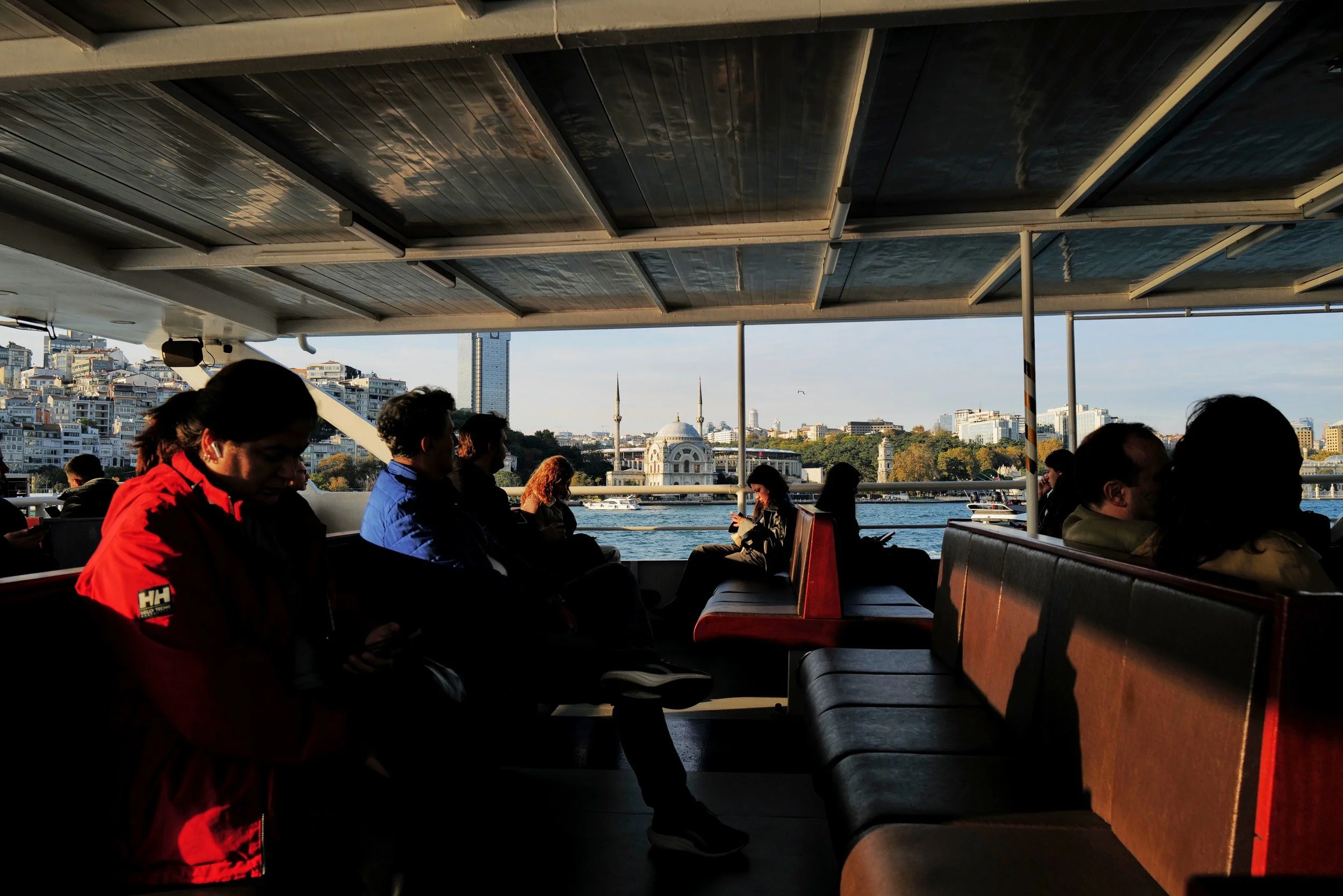 Passengers aboard a ferry in the late afternoon light
