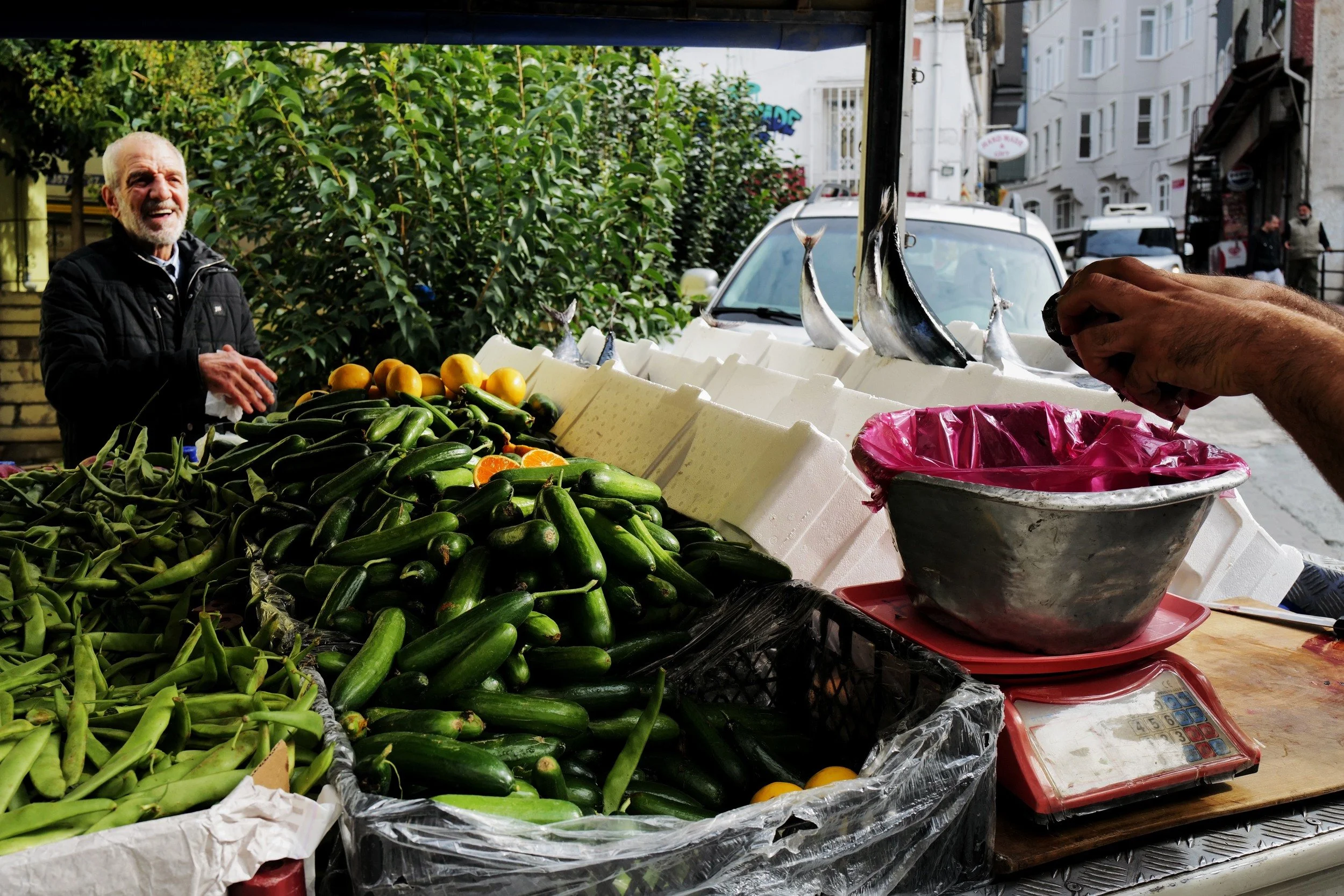 A street vendor beside a cart of pickled vegetables