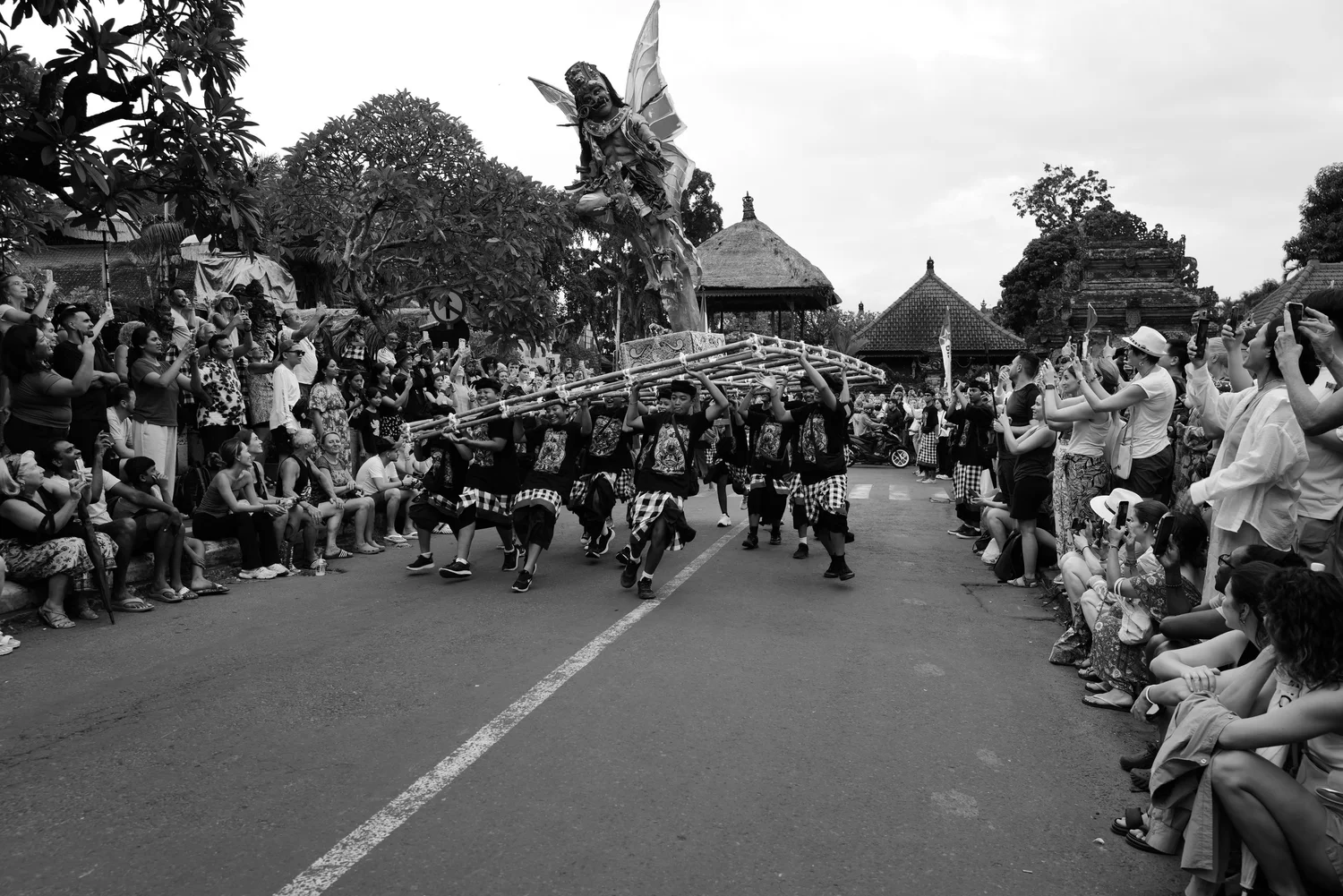 Ogoh-Ogoh carriers moving down a street lined with spectators