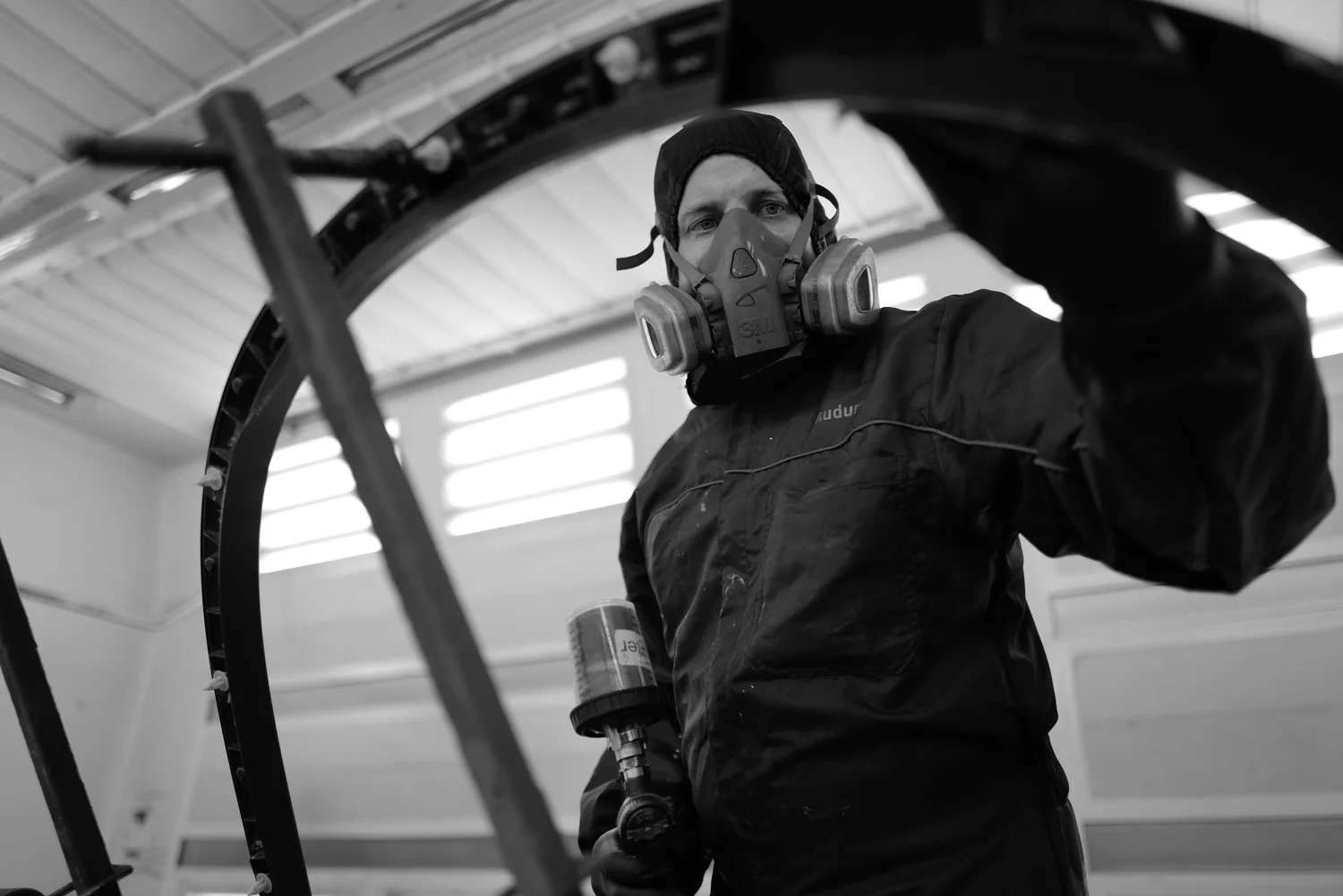 A worker with respiratory protection inside a vehicle frame