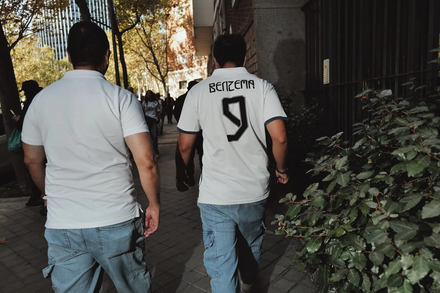 Two supporters walking along a Madrid pavement